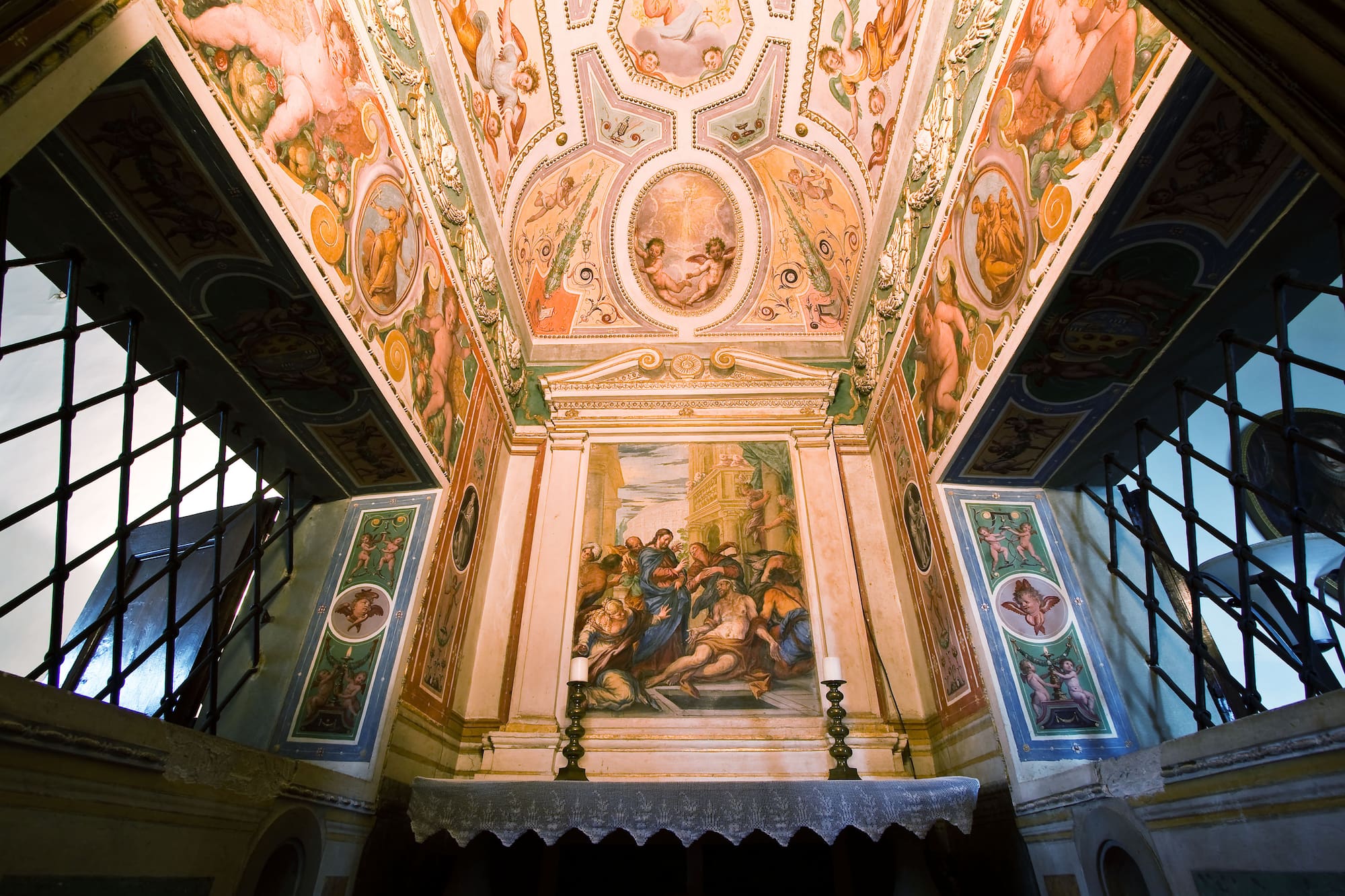 Ornate Renaissance chapel with elaborate ceiling frescoes and religious altar mural.