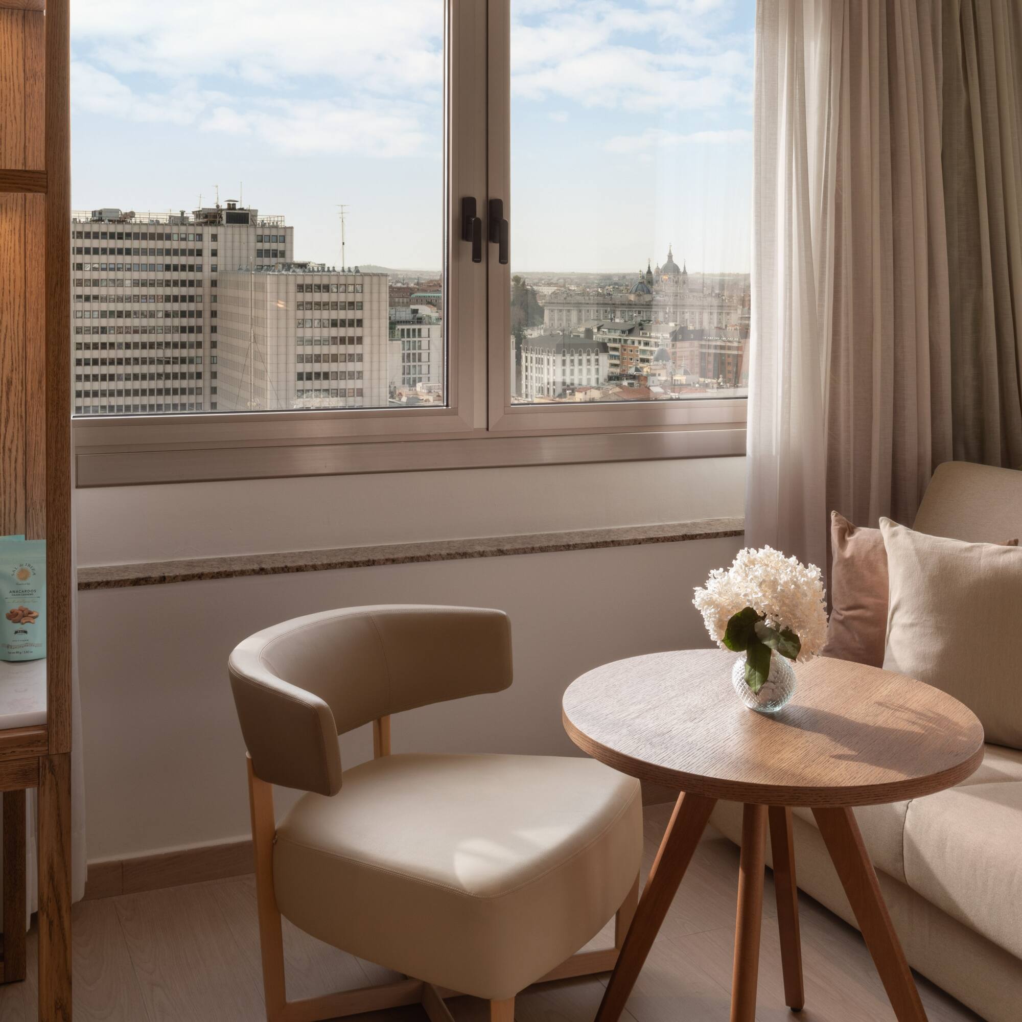 Luxury hotel room in Madrid with city view, comfortable seating, and minibar.