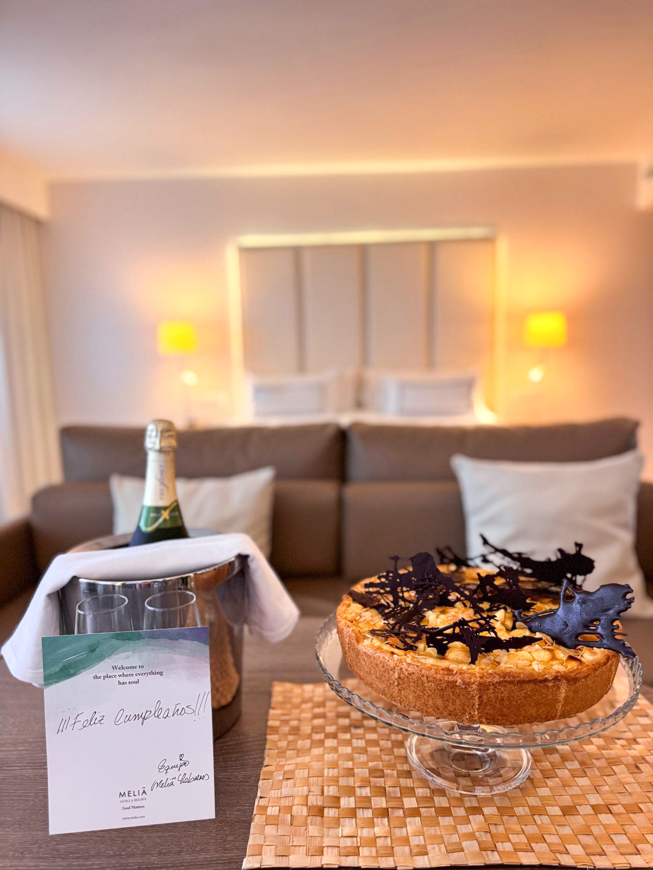 Meliá birthday welcome: champagne, cake with chocolate dinosaurs, Happy Birthday card.