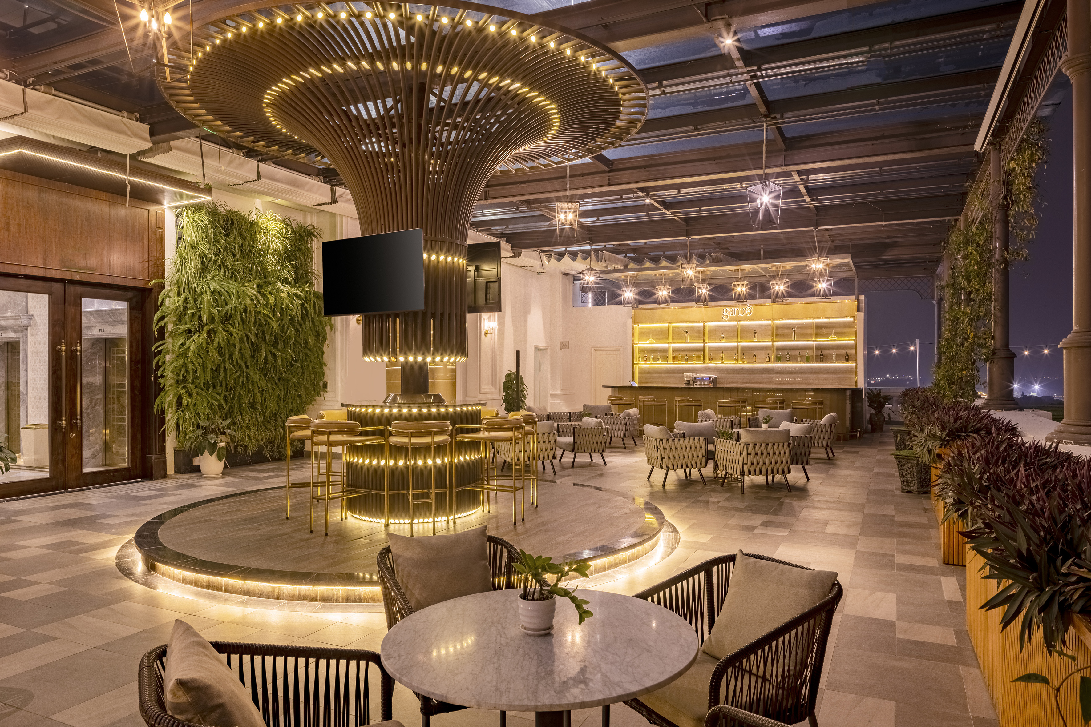 Elegant rooftop bar with illuminated central counter, living wall, and cozy seating.