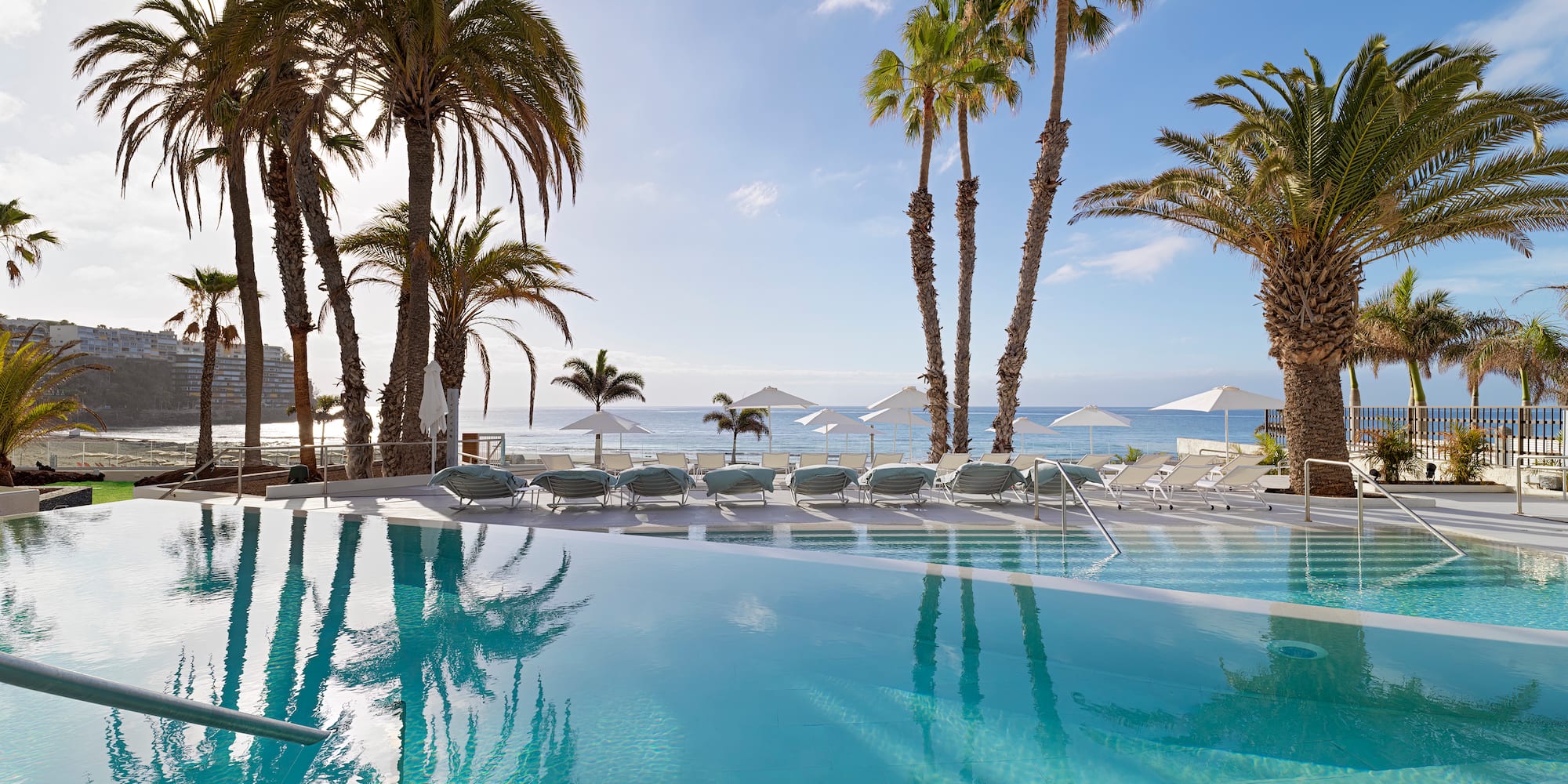 a pool with palm trees and umbrellas
