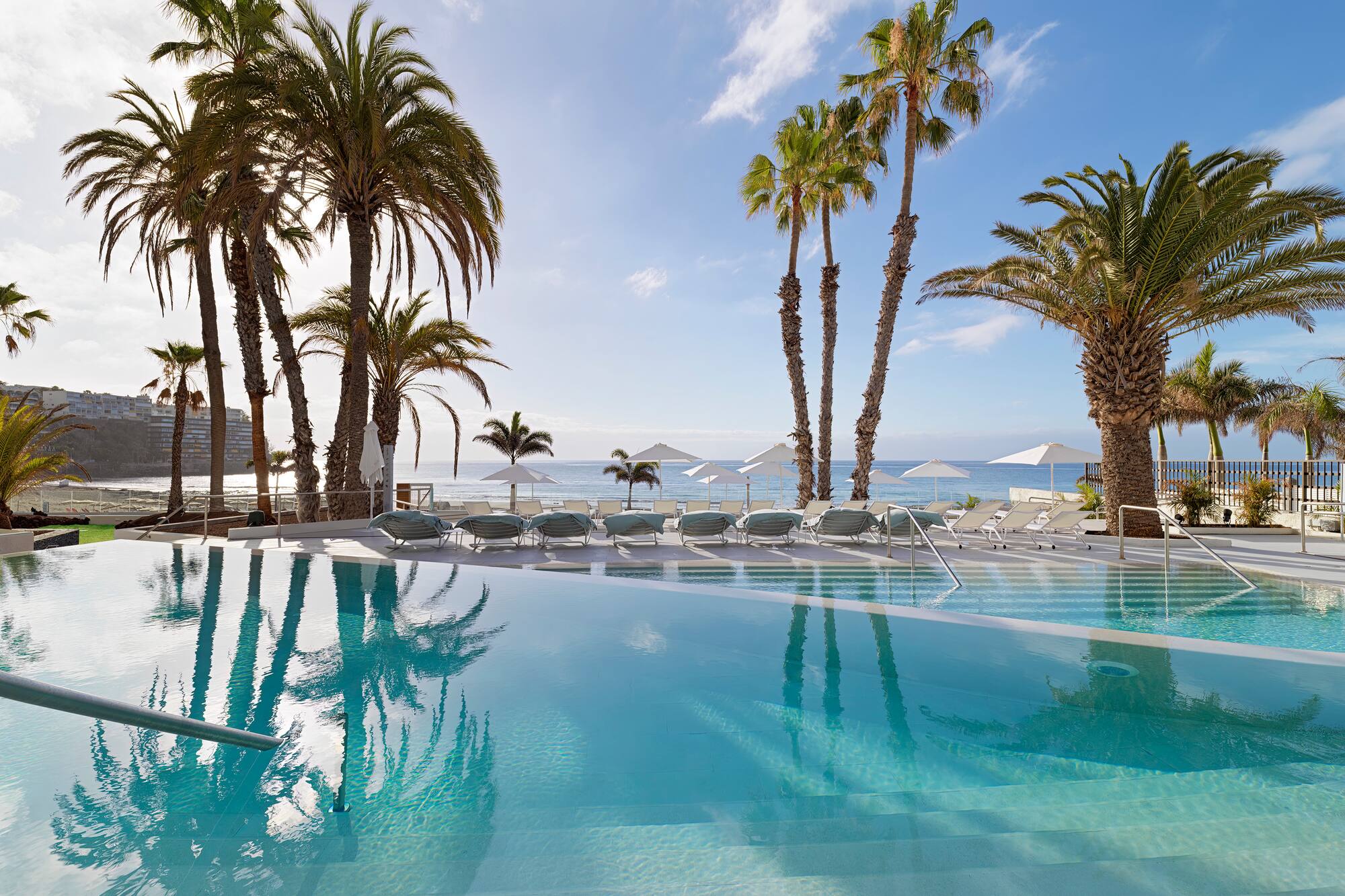 a pool with palm trees and umbrellas