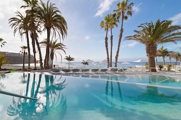 a pool with palm trees and umbrellas
