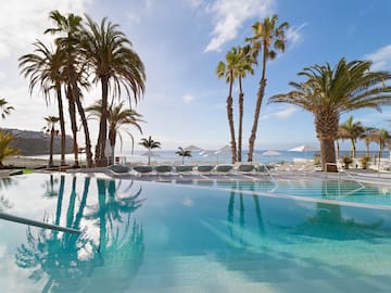 a pool with palm trees and umbrellas
