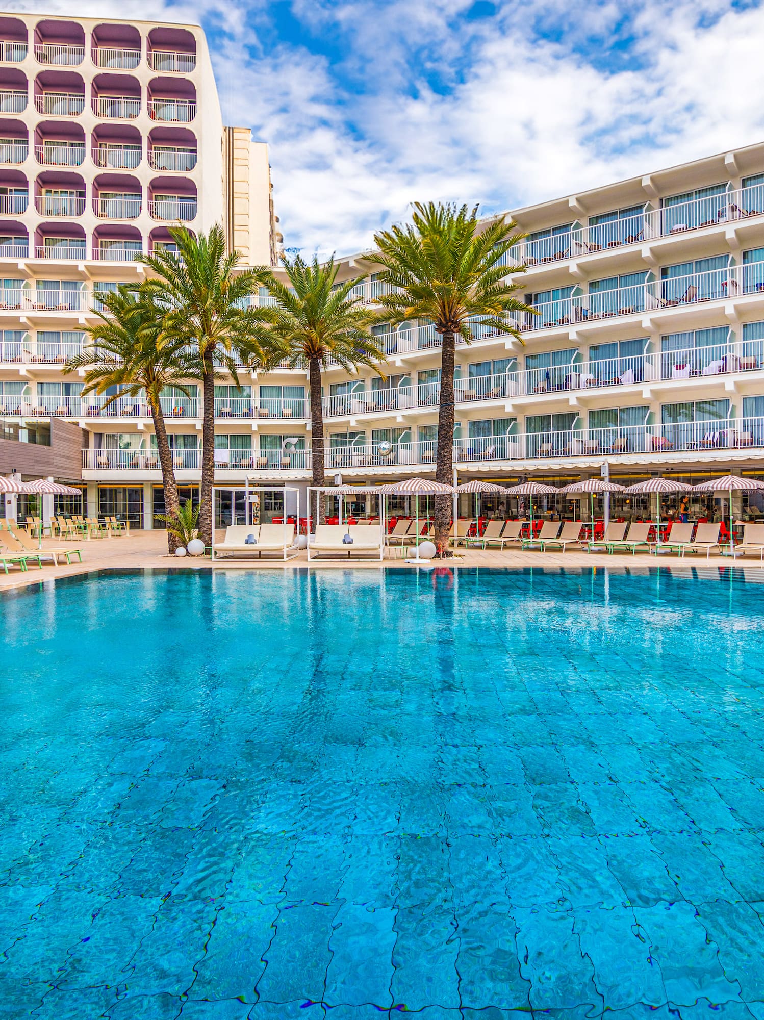 a pool with palm trees in front of a building