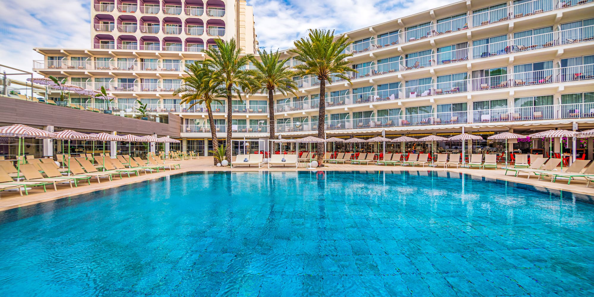 a pool with palm trees in front of a building