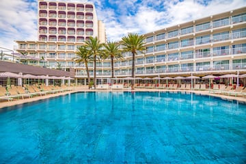 a pool with palm trees in front of a building