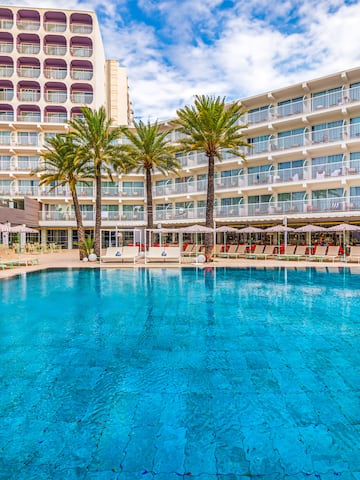 a pool with palm trees in front of a building