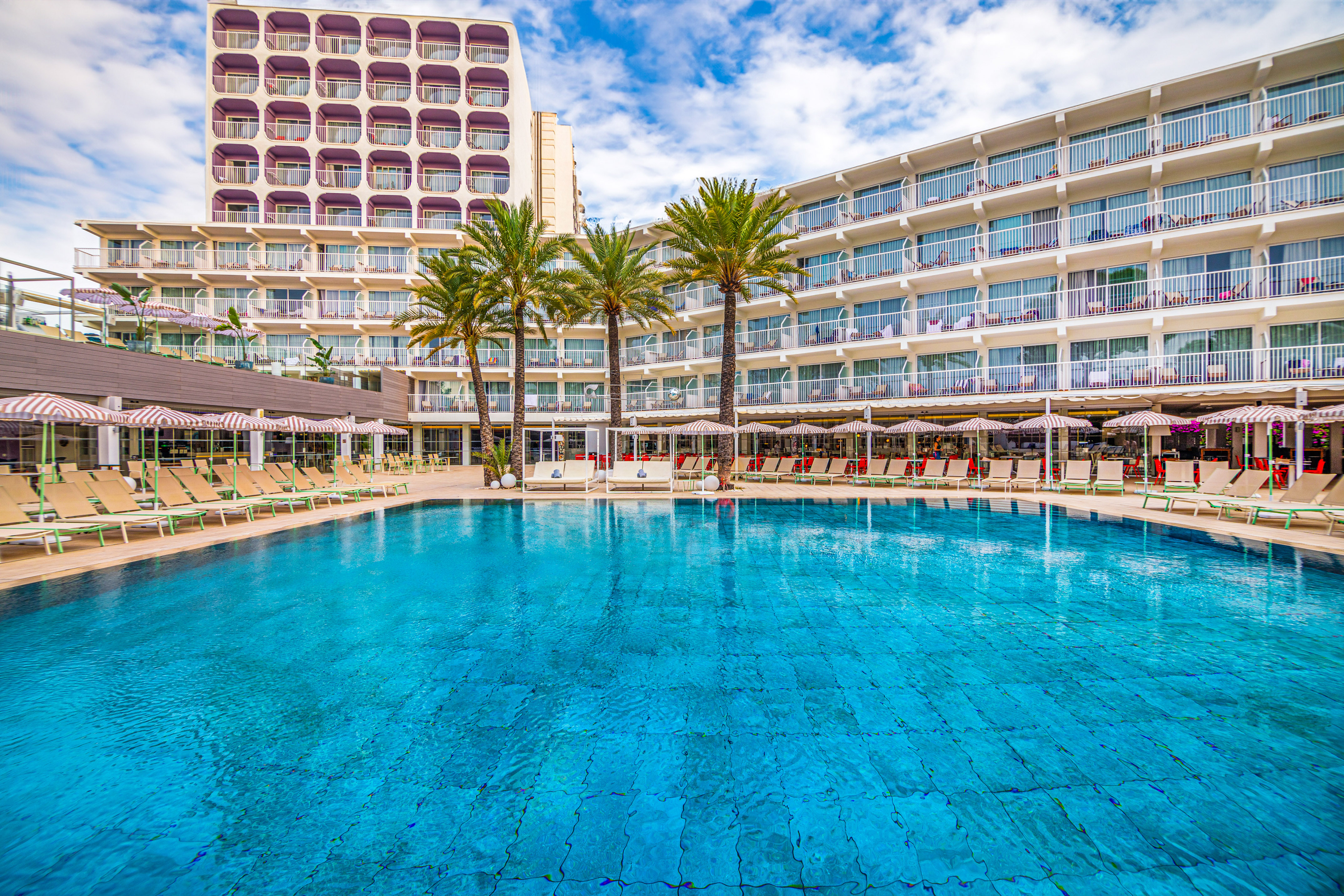 a pool with palm trees in front of a building