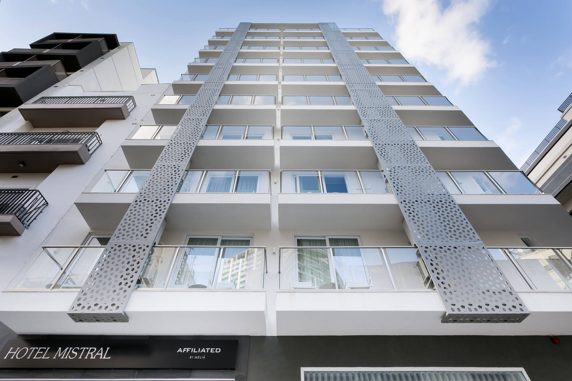 Hotel Mistral's modern exterior facade with balconies and perforated gray panels.
