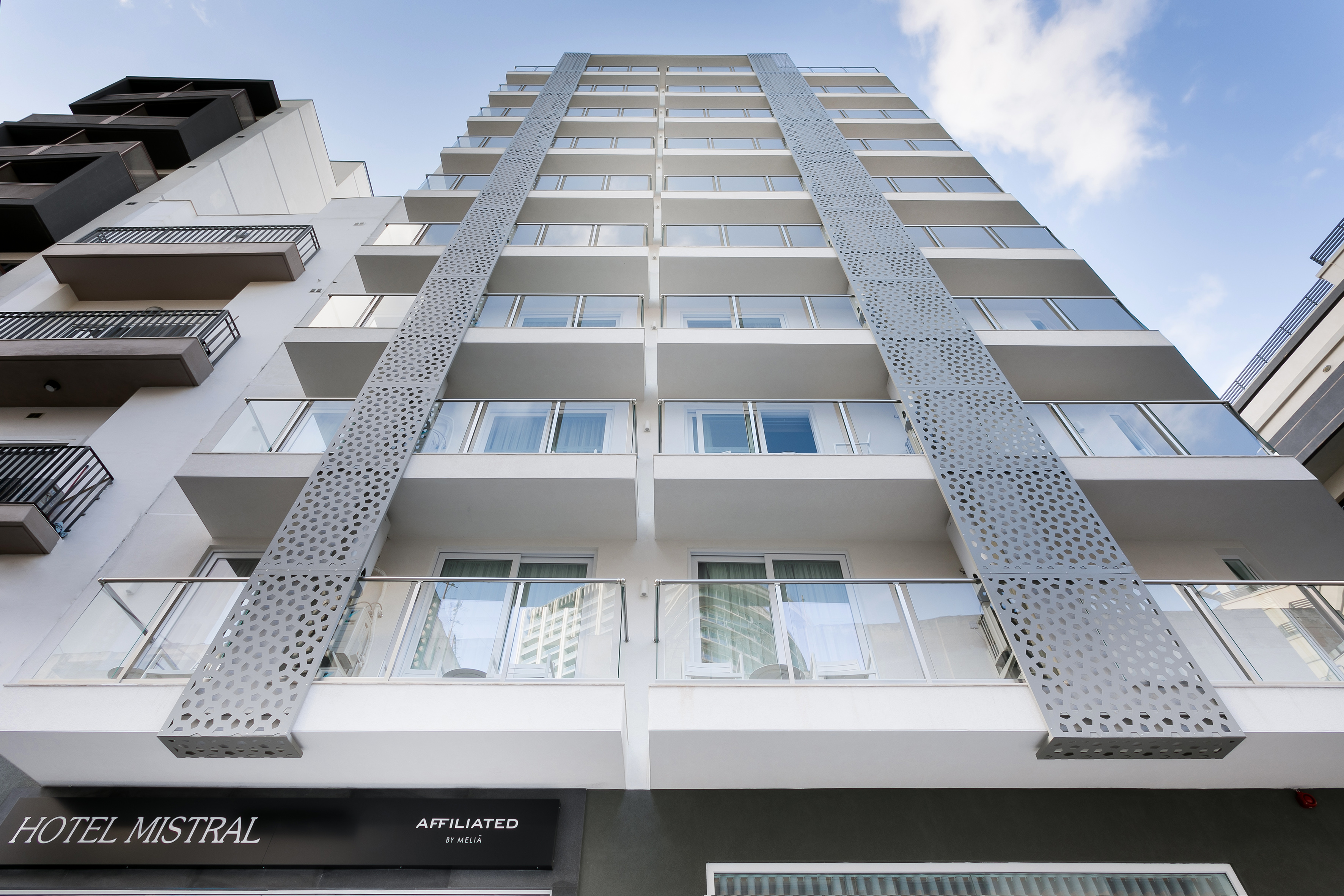 Hotel Mistral's modern exterior facade with balconies and perforated gray panels.