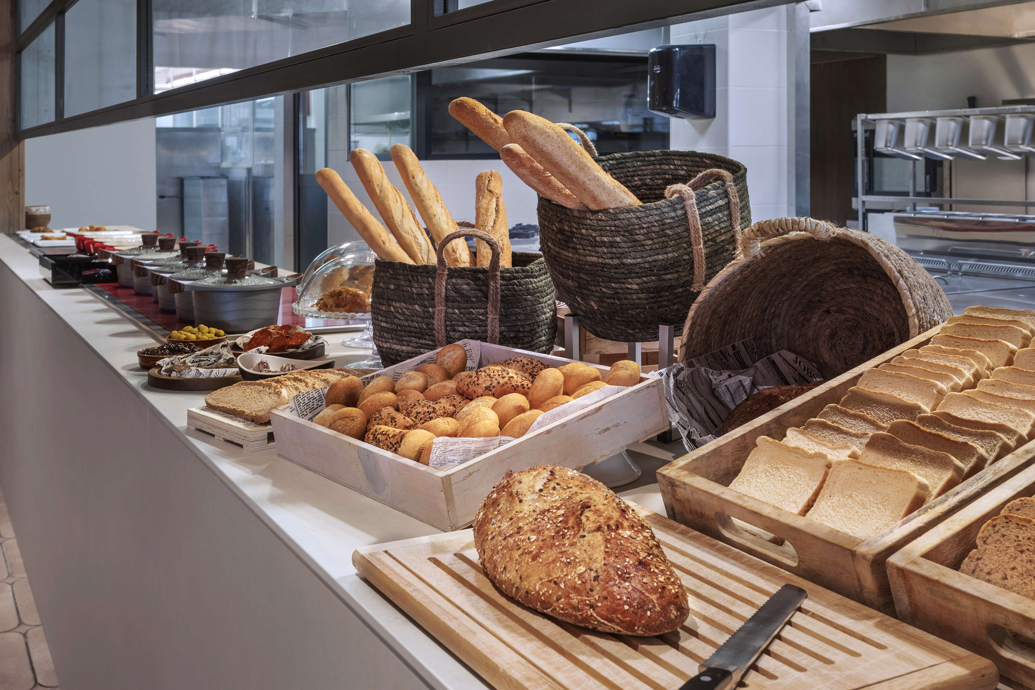 Fresh bread, rolls, and hot dishes at a hotel breakfast buffet.
