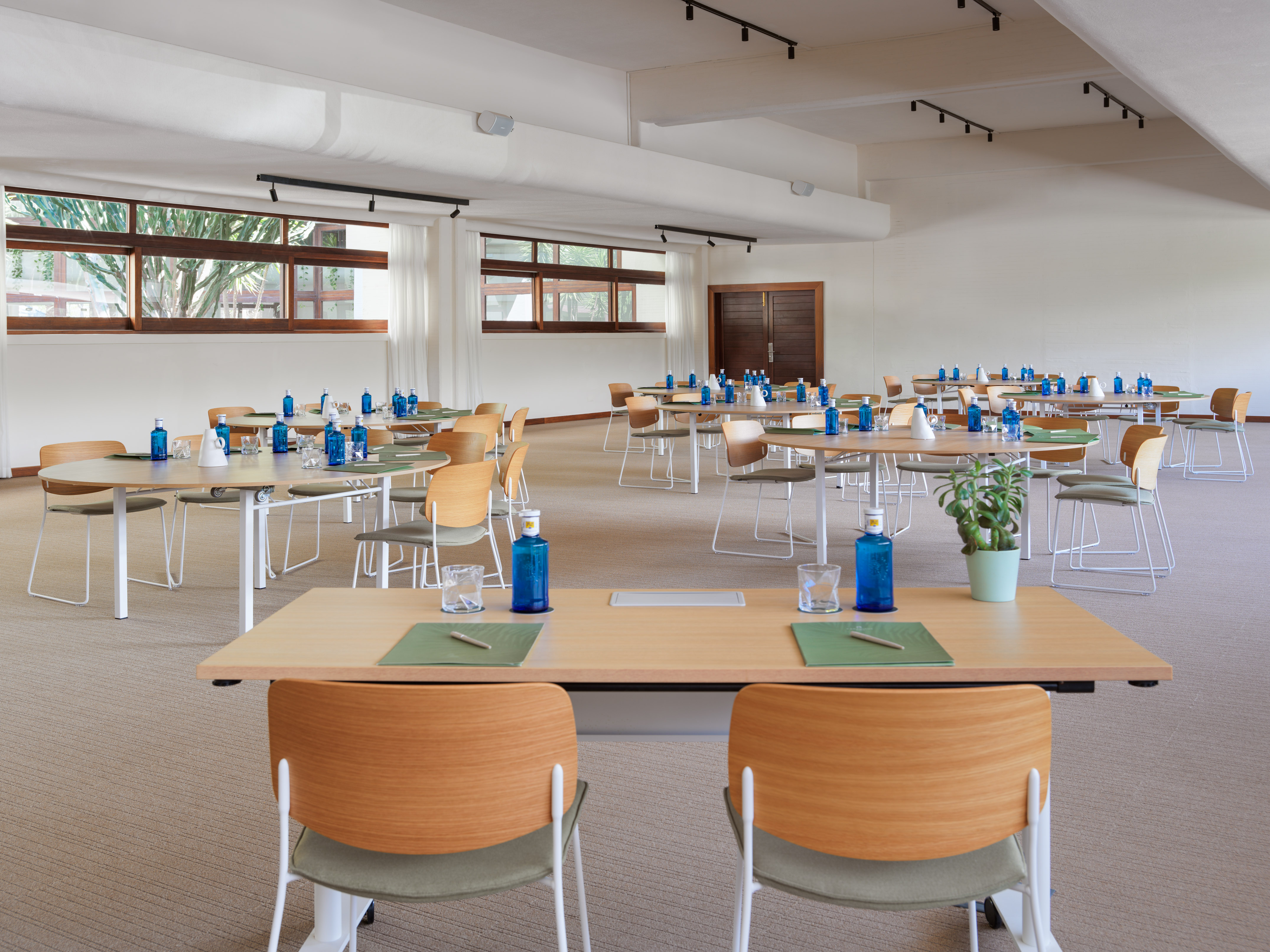 Bright conference room with modern tables, chairs, and blue water bottles.