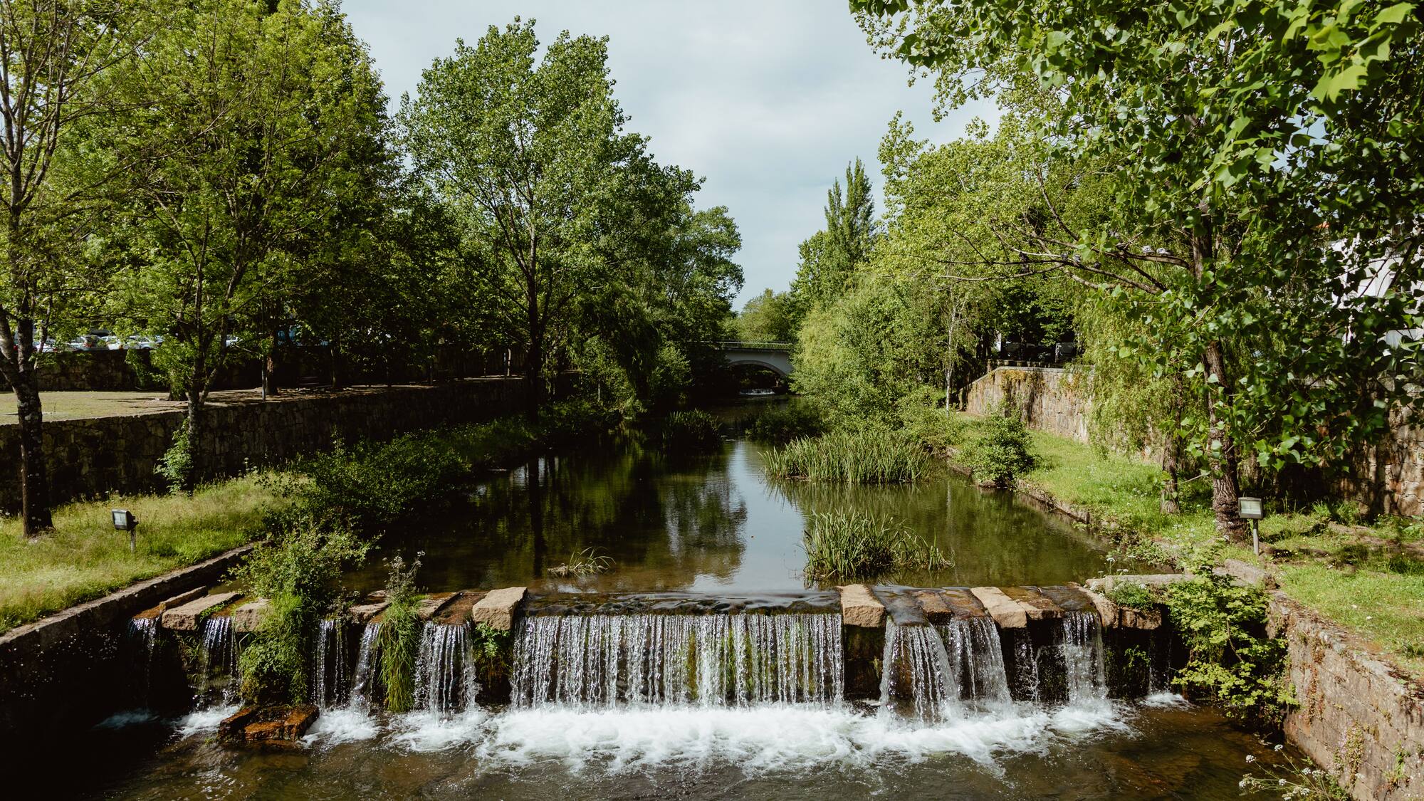 a river with a waterfall and trees