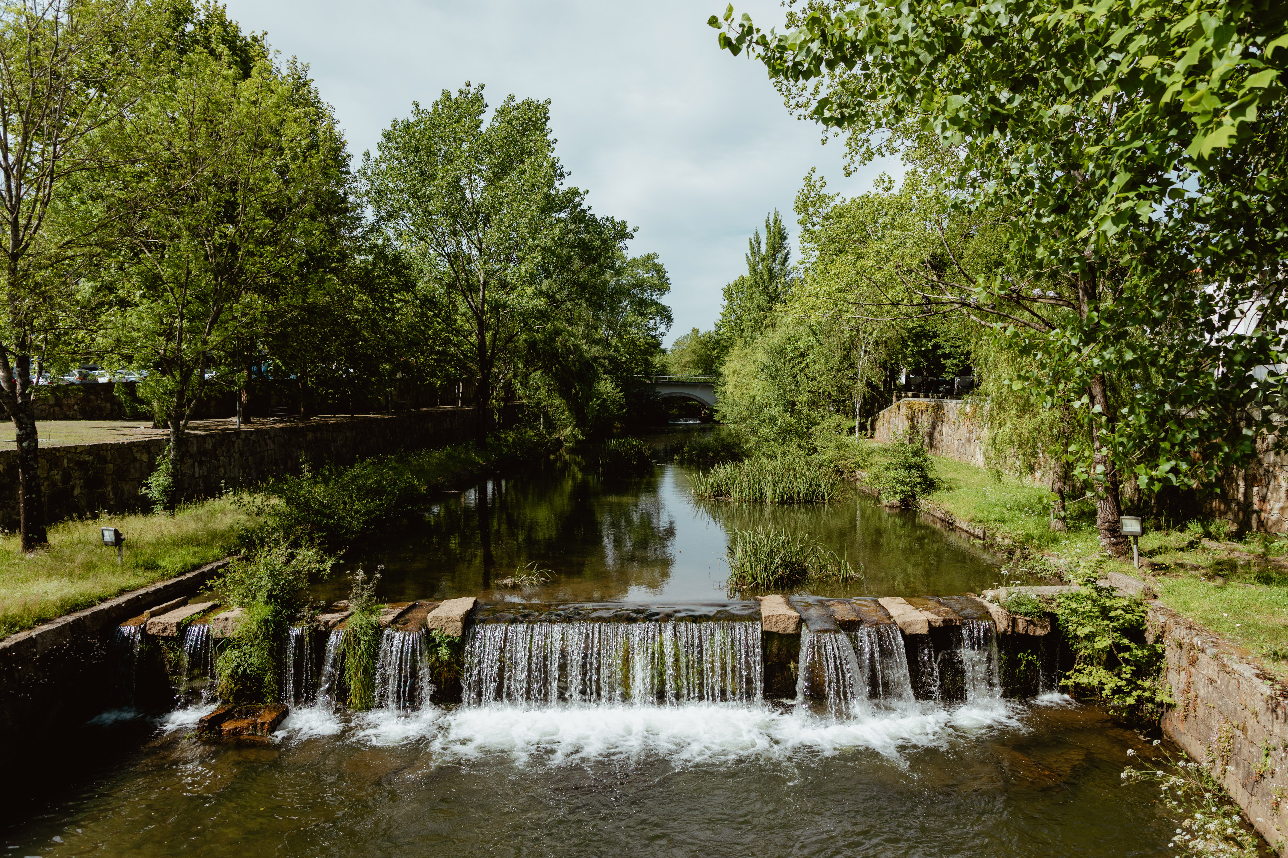 a river with a waterfall and trees