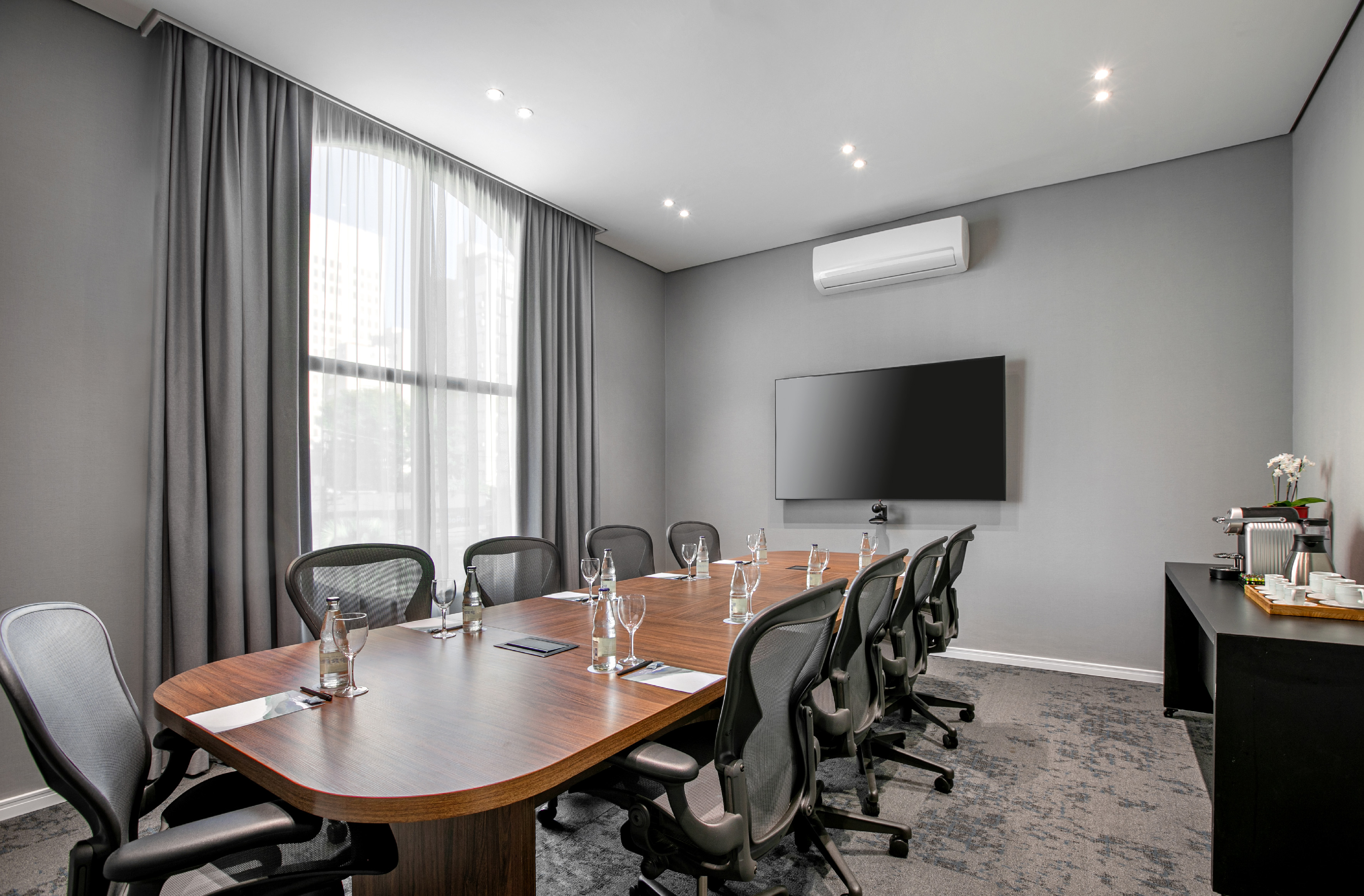 Modern conference room with wood table, ergonomic chairs, and TV.