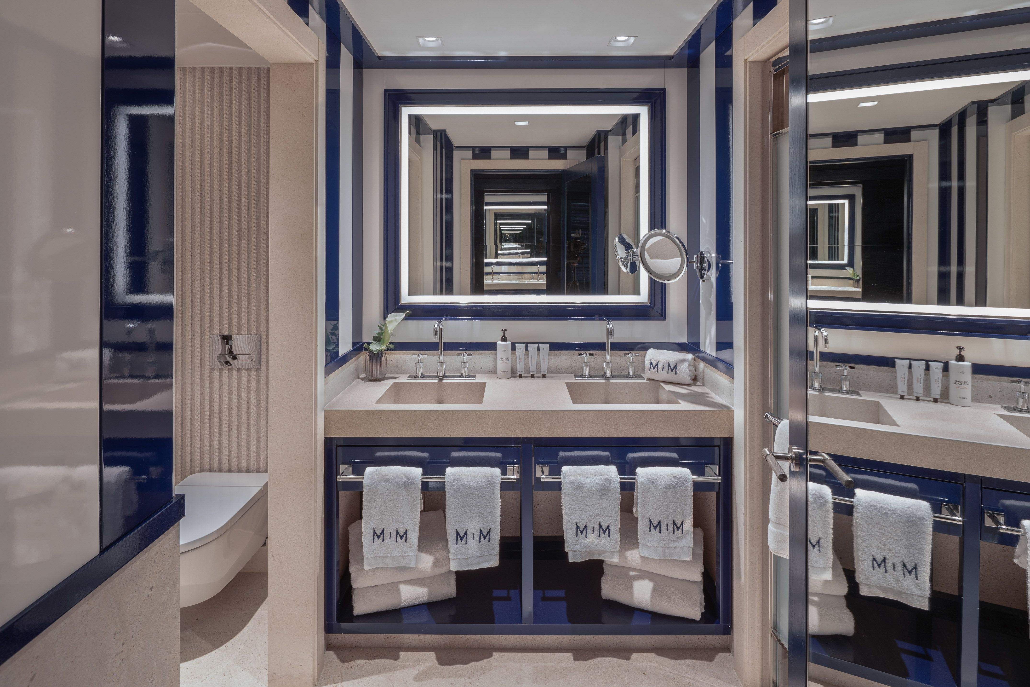 Sleek blue and white striped bathroom, double vanity, illuminated mirror.