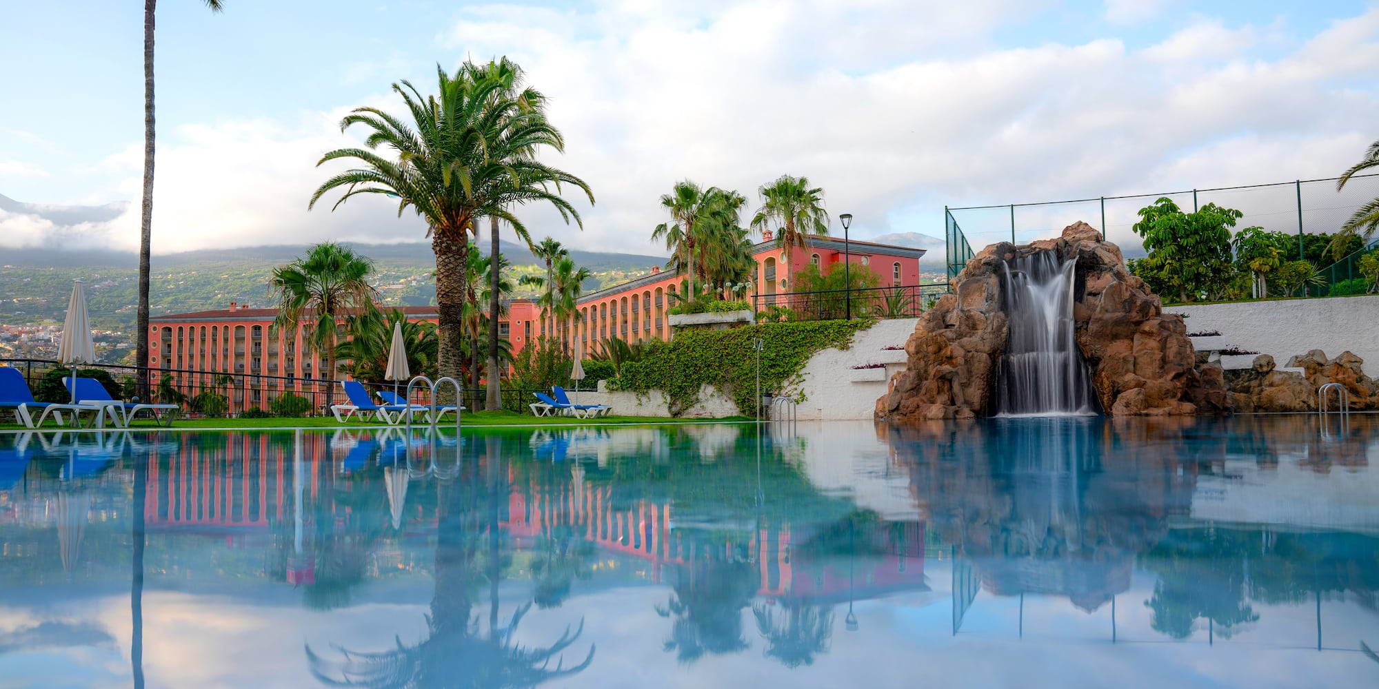 a pool with a waterfall and palm trees