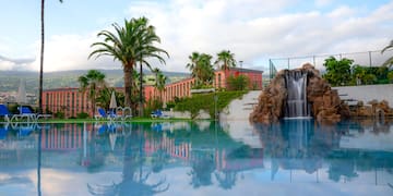 a pool with a waterfall and palm trees