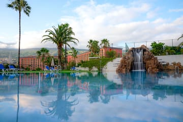 a pool with a waterfall and palm trees
