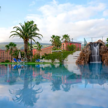 a pool with a waterfall and palm trees
