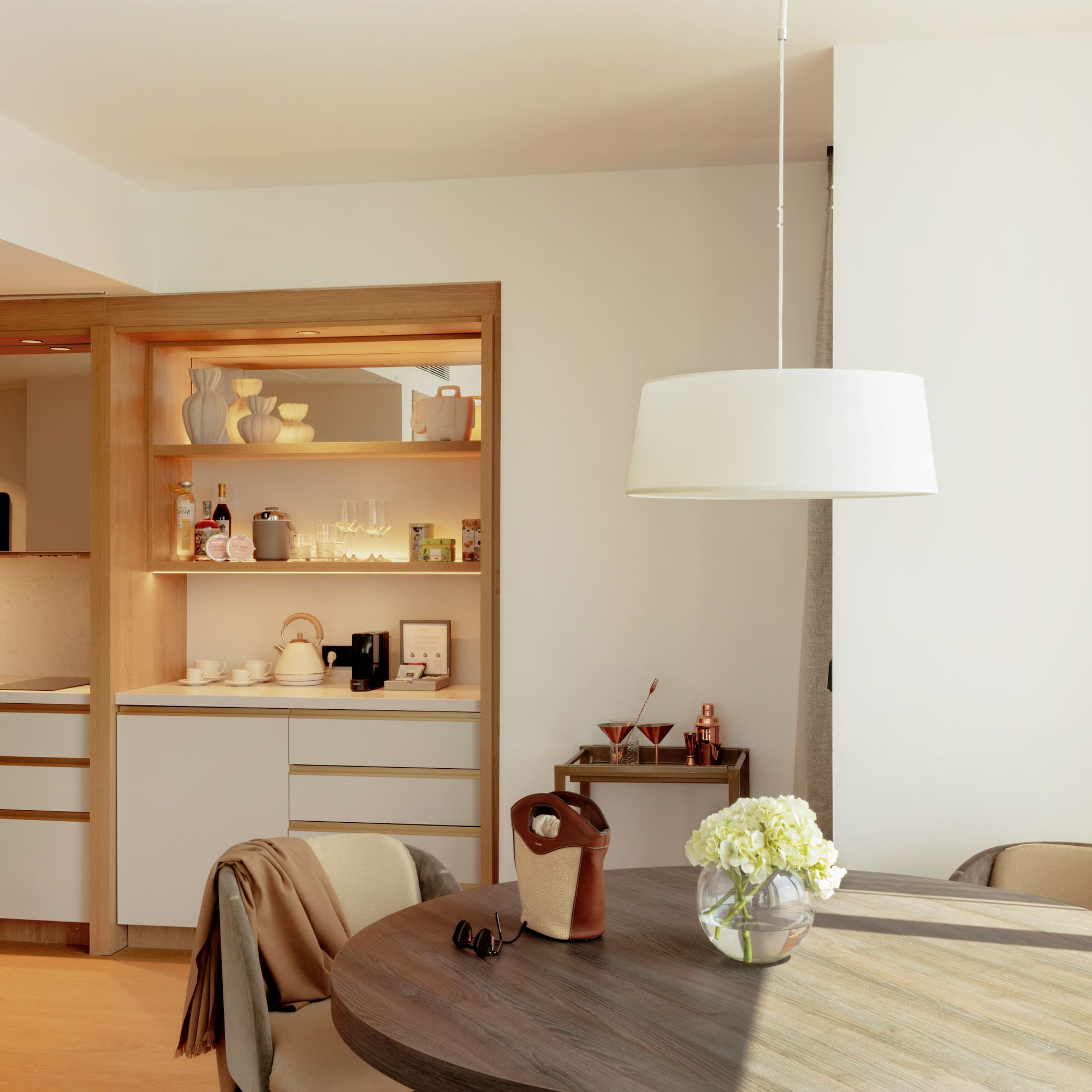 Bright hotel suite interior featuring a modern kitchenette and round dining table.
