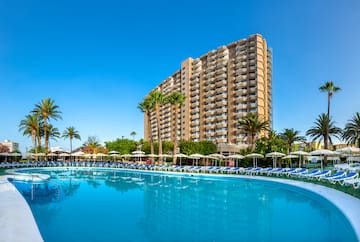 a pool with lounge chairs and a building in the background