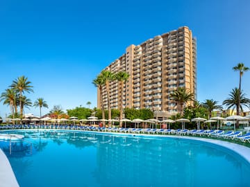 a pool with lounge chairs and a building in the background