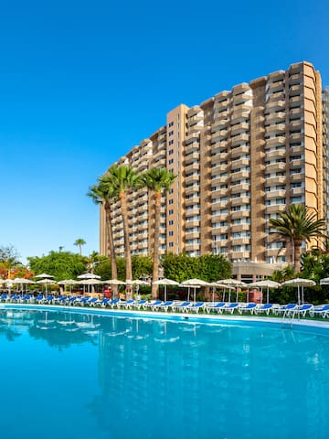 a pool with lounge chairs and a building in the background