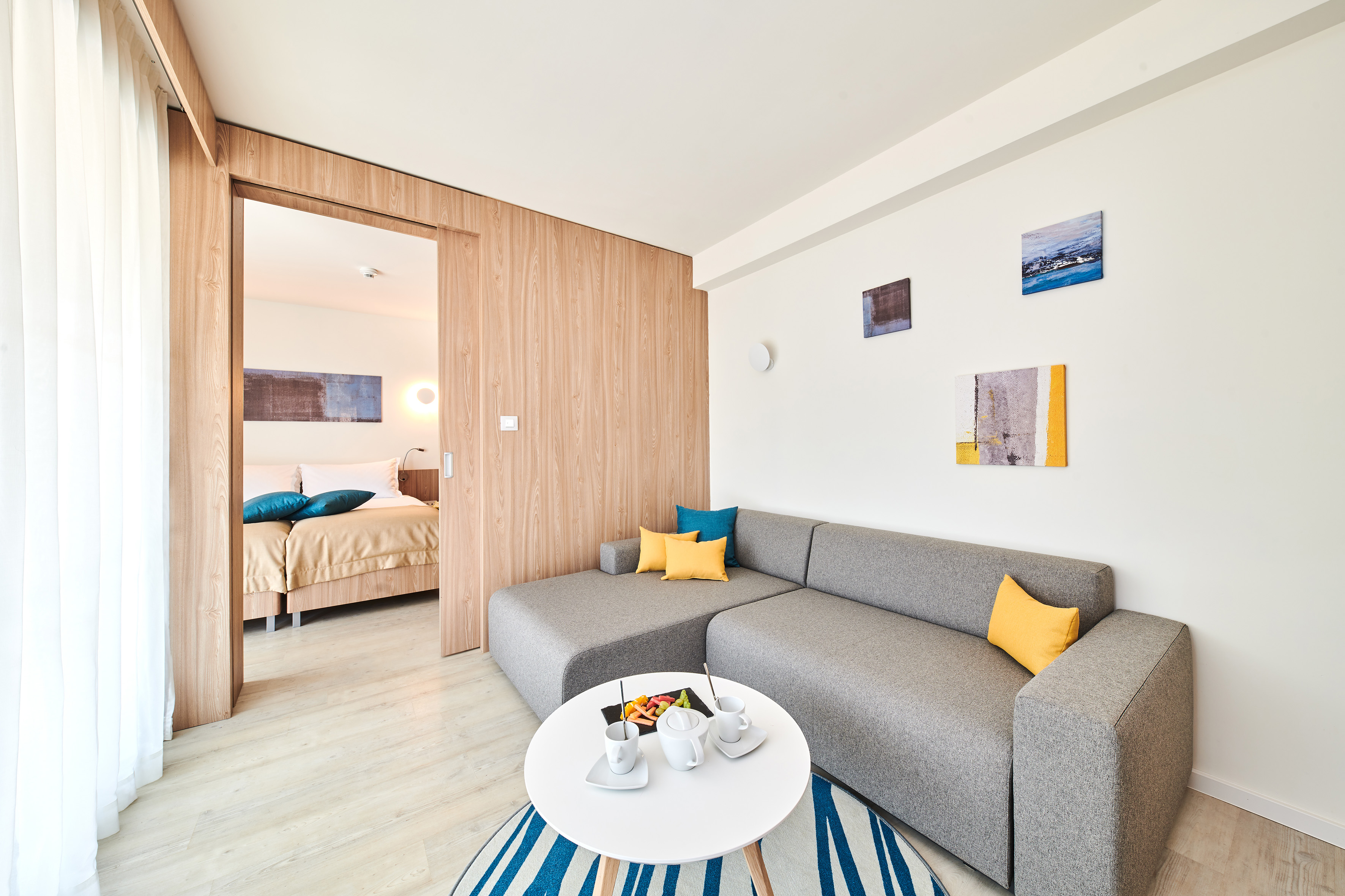 a living room with a couch and a small table - Suite - Garden Suites Umag Plava Laguna Affiliated by Meliá, Umag