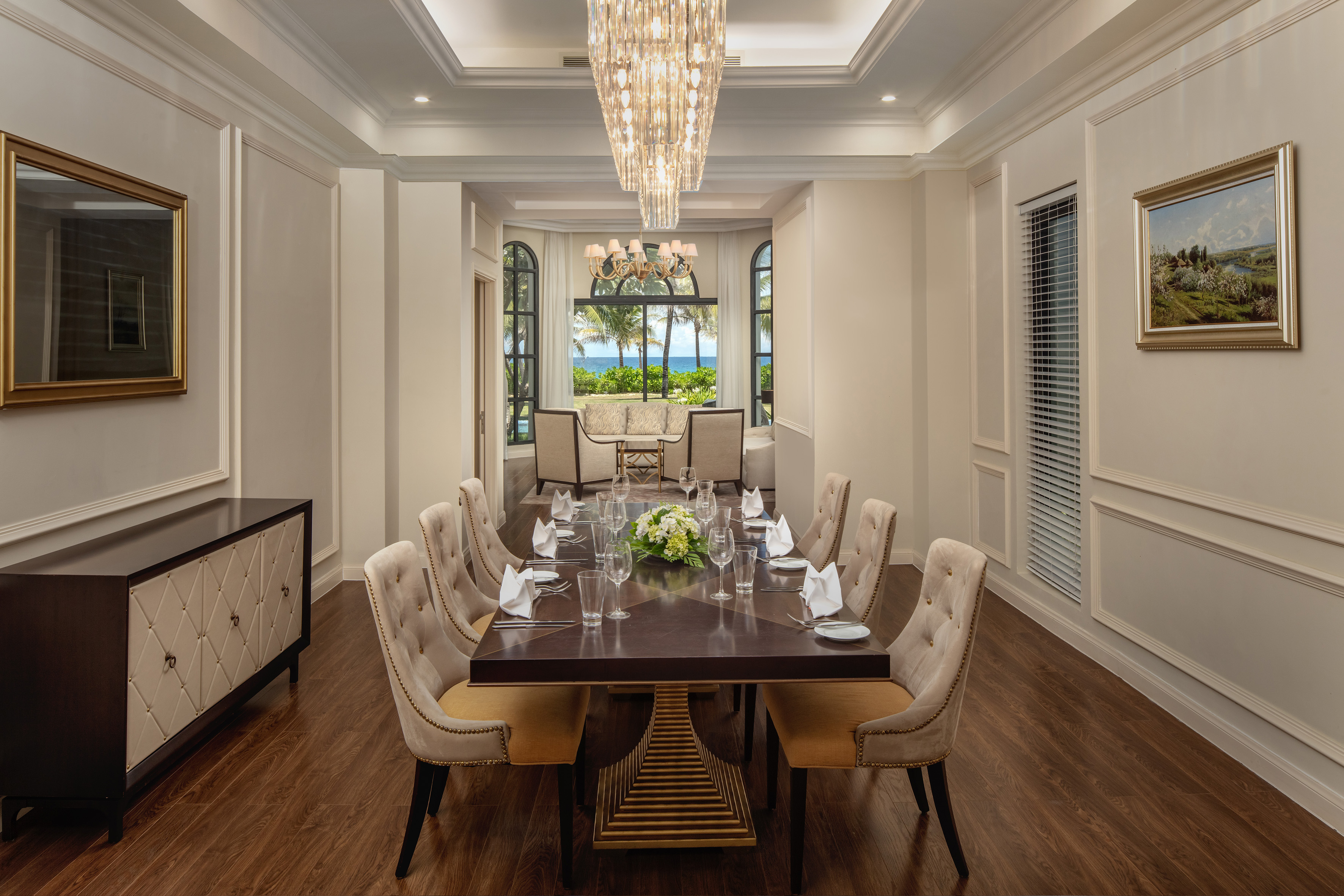 Luxury dining room with ocean view, elegant table setting, and grand chandelier.