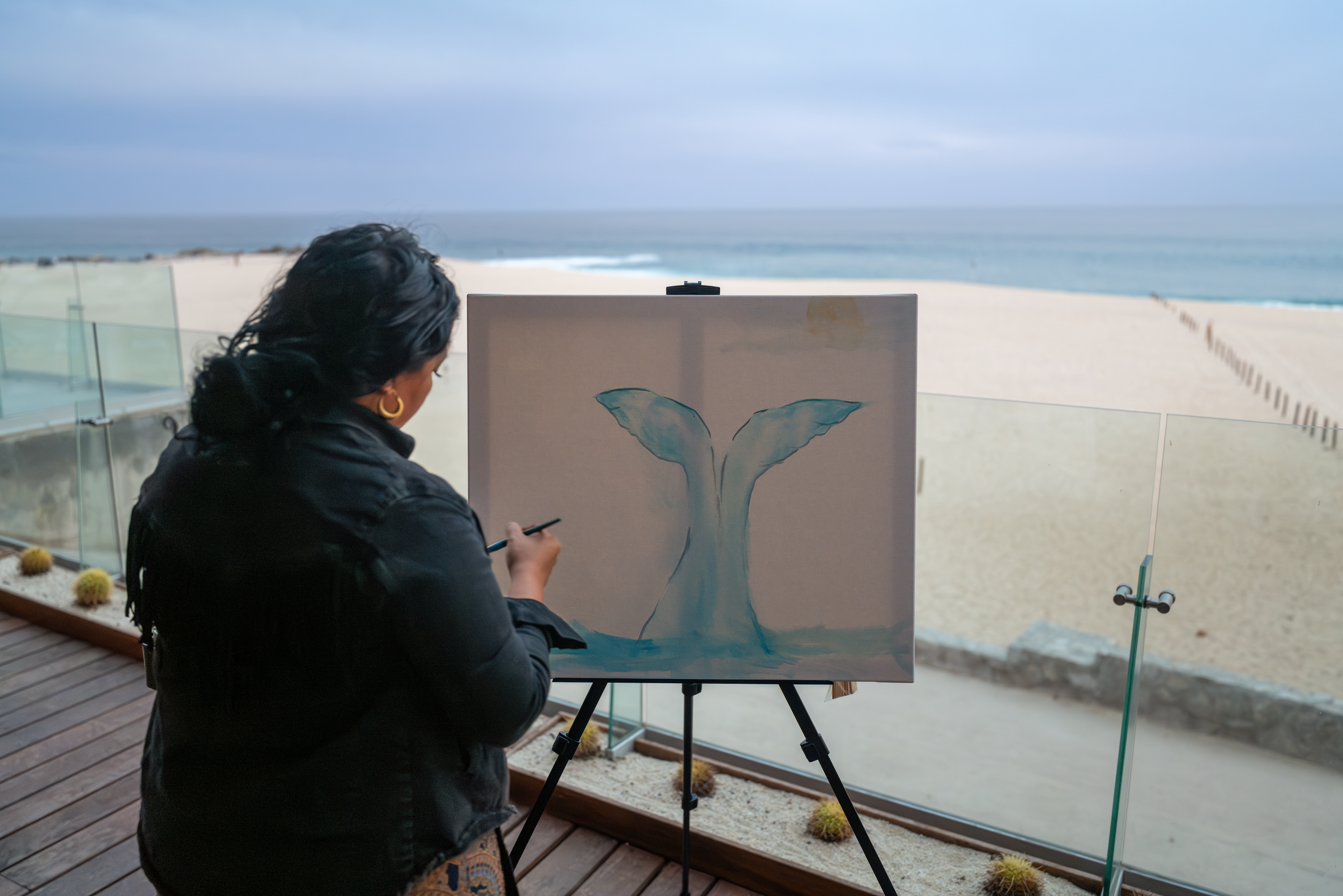 a woman painting a whale tail on canvas