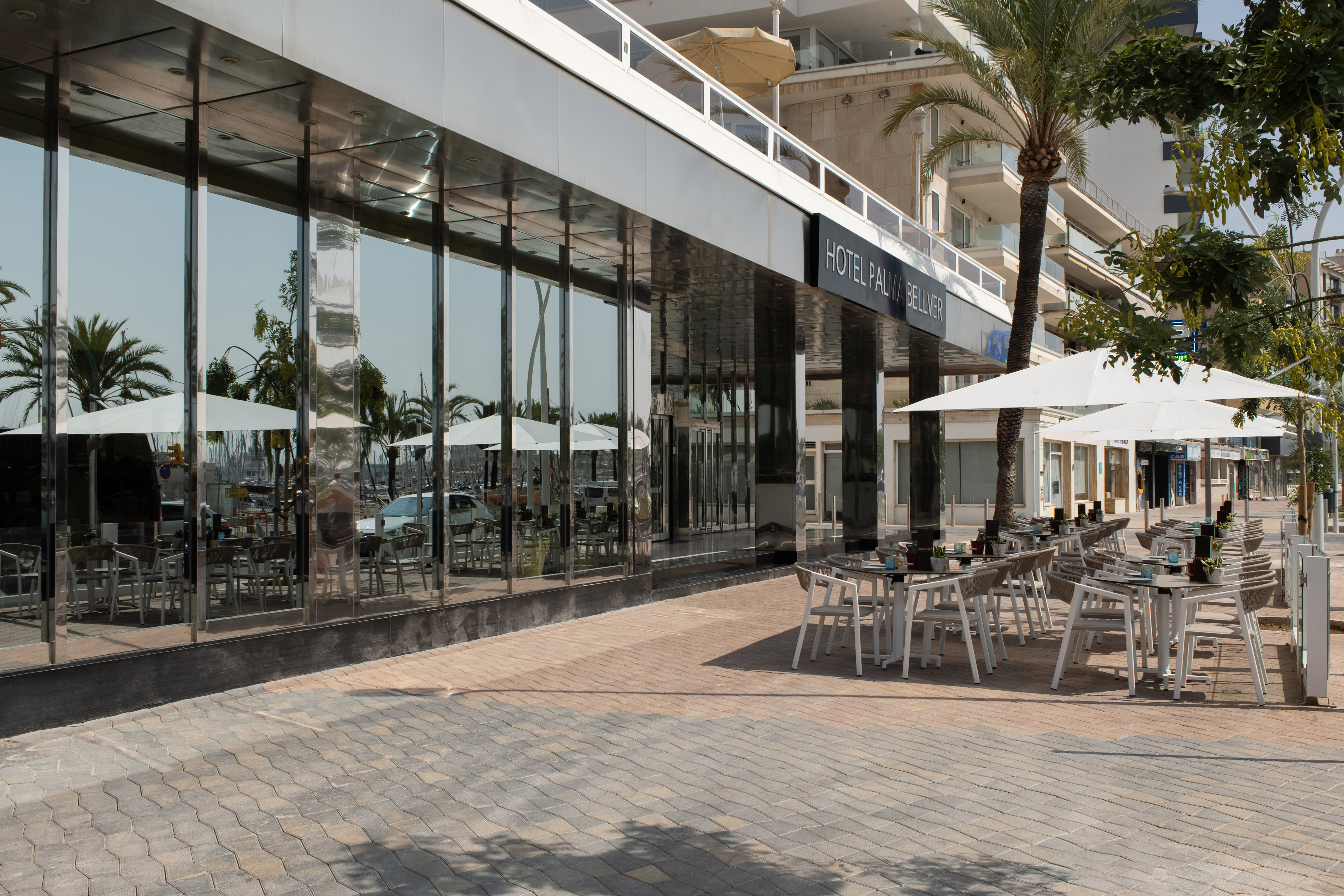 Hotel Palma Bellver outdoor patio with white umbrellas and marina reflections.