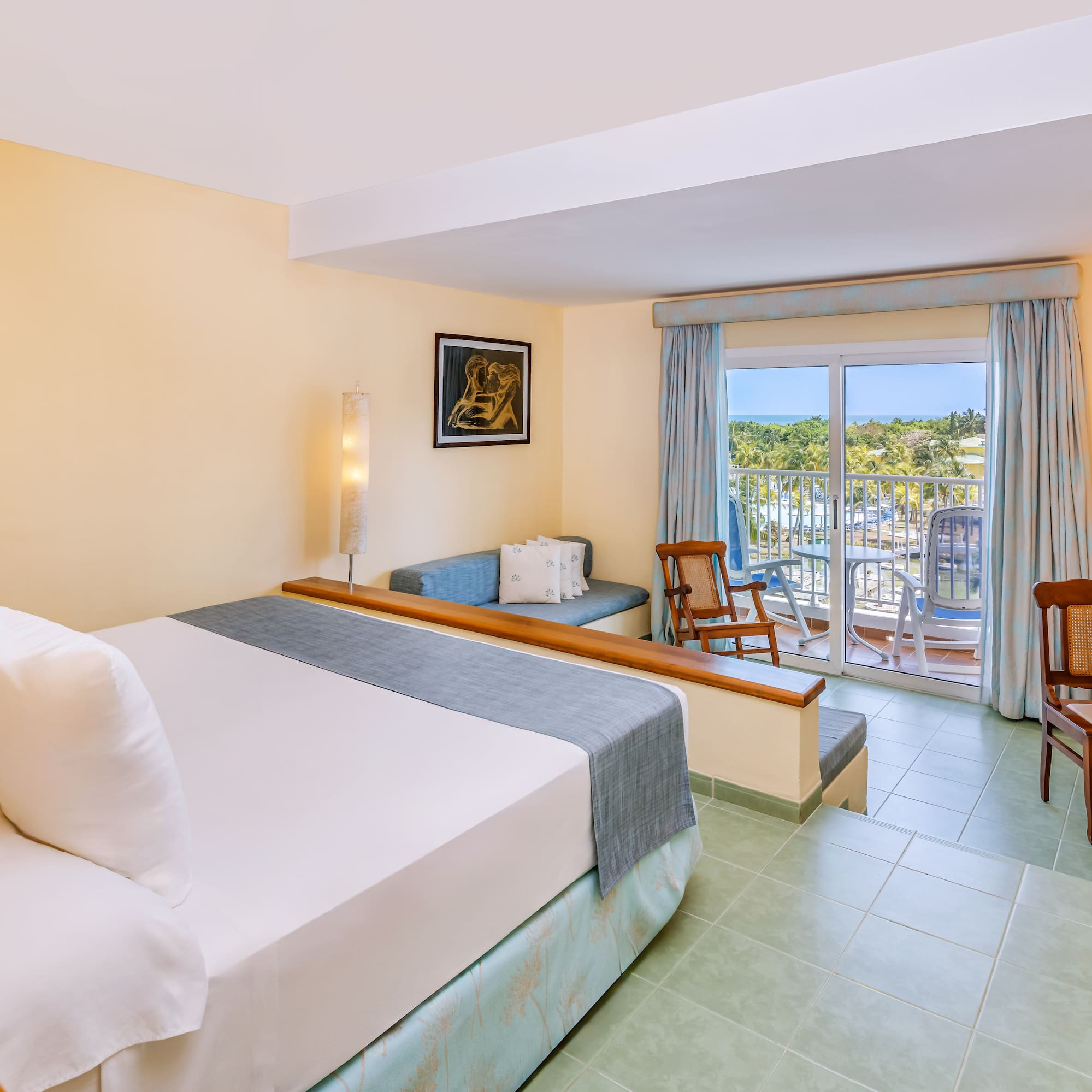 a room with a bed and chairs and a balcony