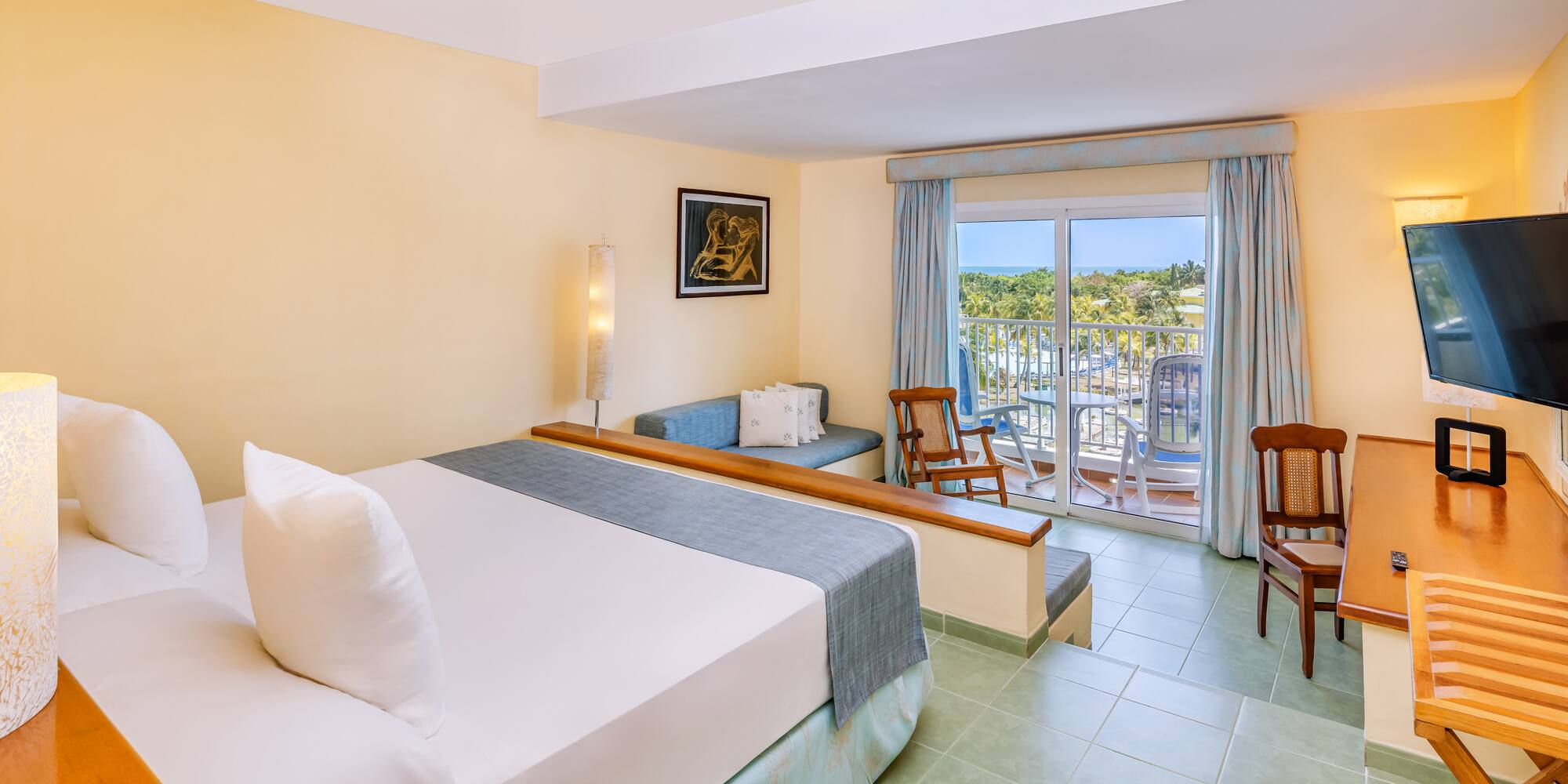 a room with a bed and chairs and a balcony