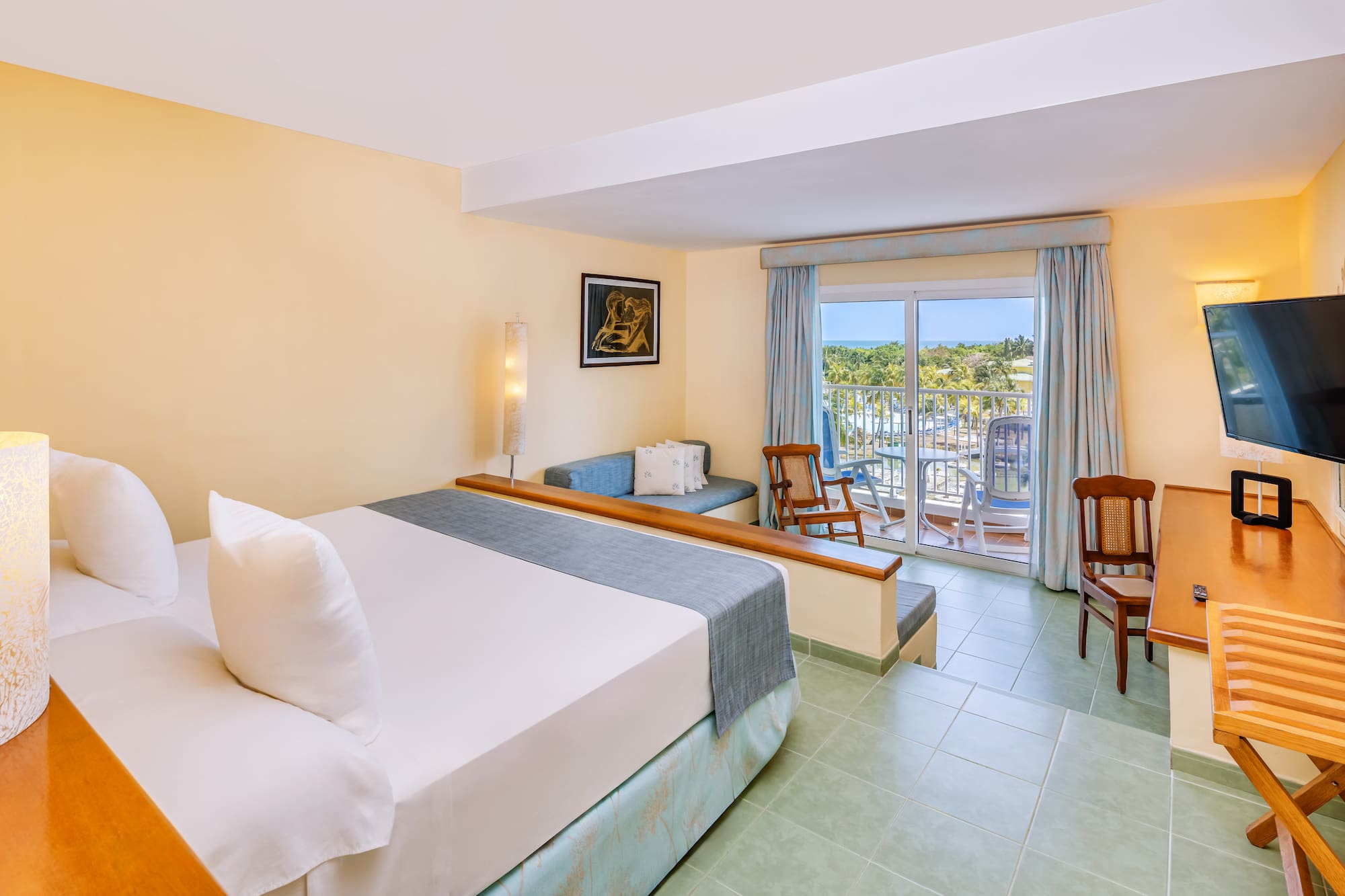 a room with a bed and chairs and a balcony