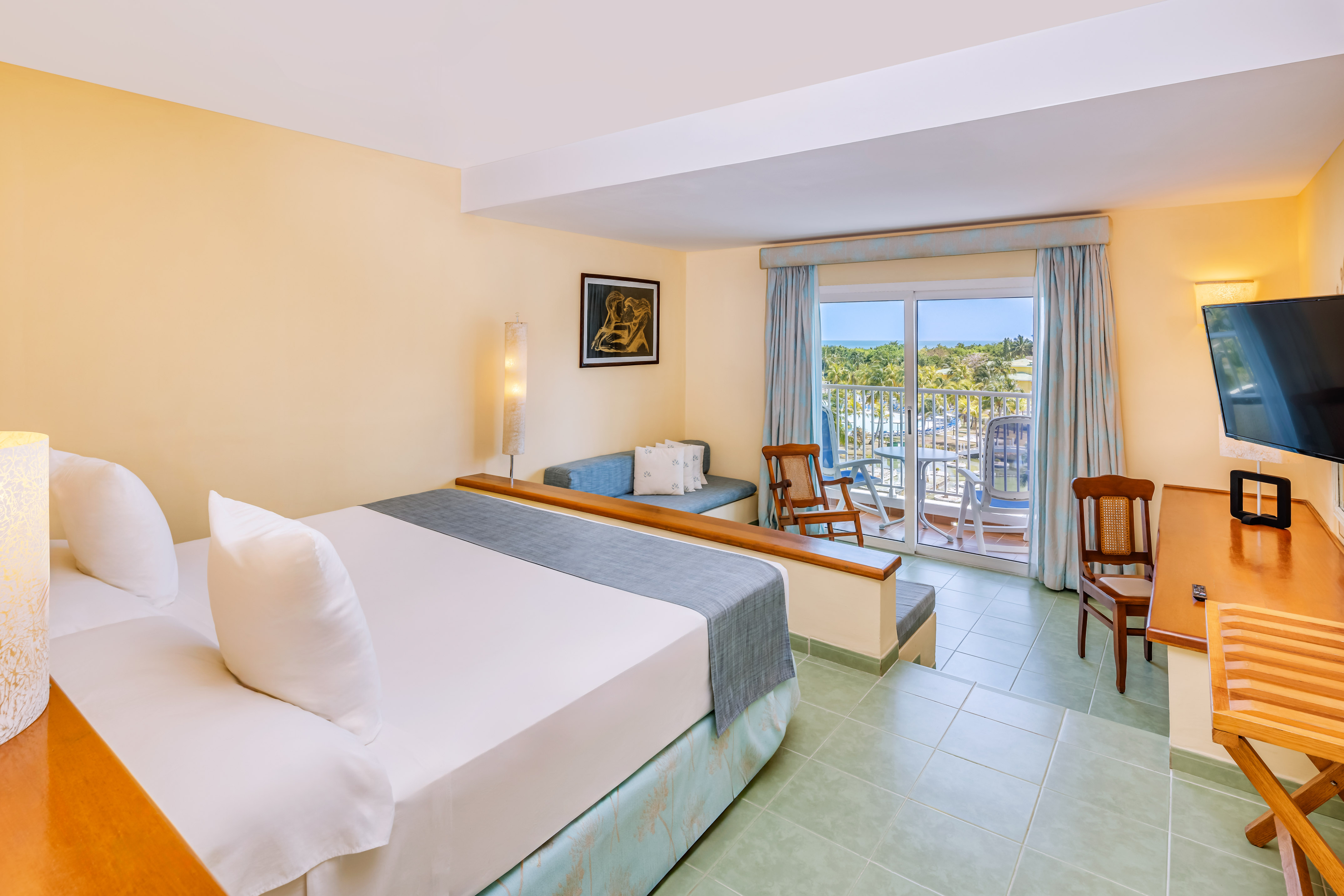 a room with a bed and chairs and a balcony