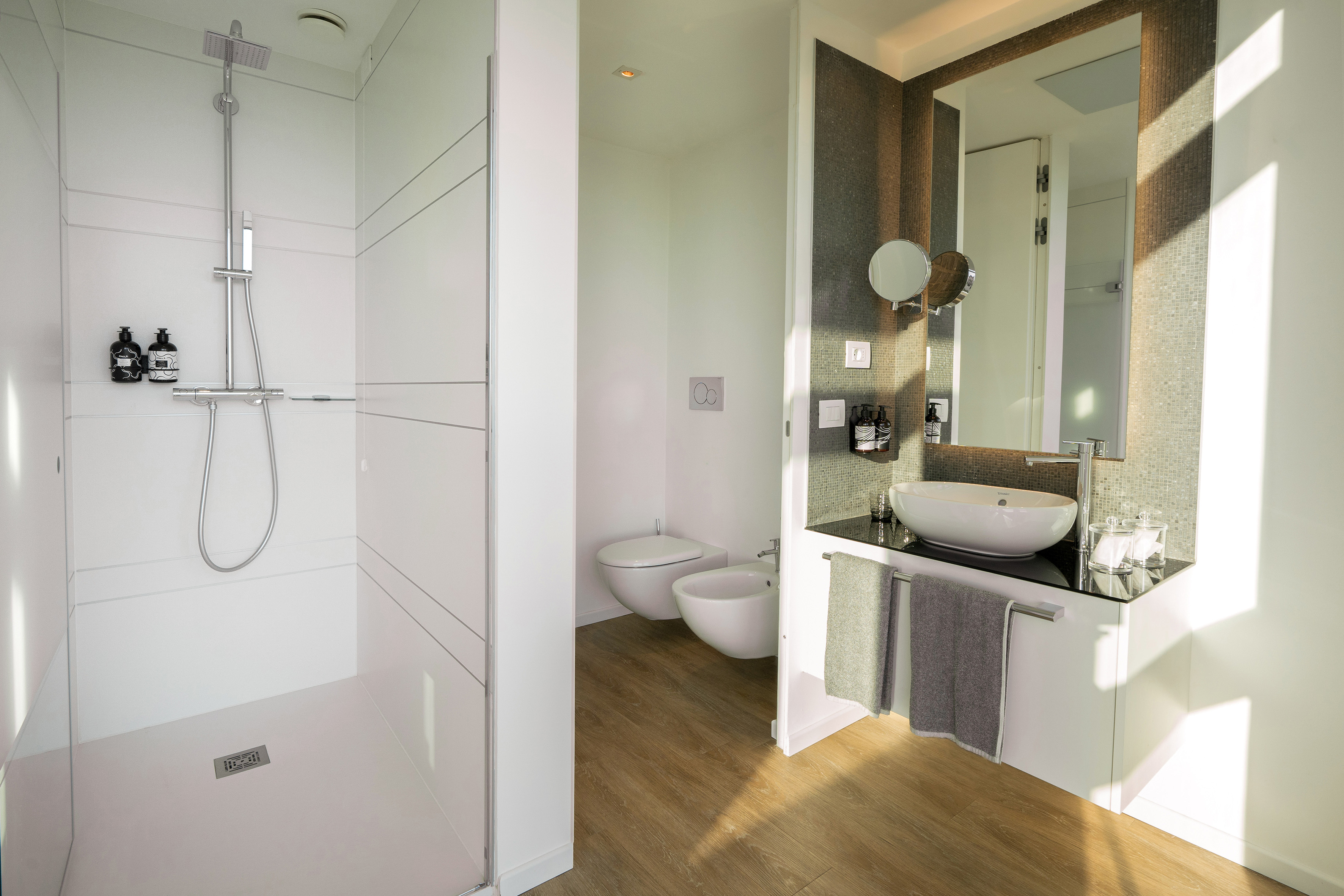 Modern hotel bathroom with walk-in shower, toilet, bidet, and vanity.
