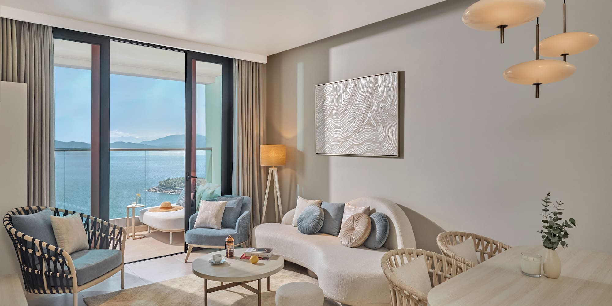 Elegant living room with sea view balcony, curved sofa, and modern interior.