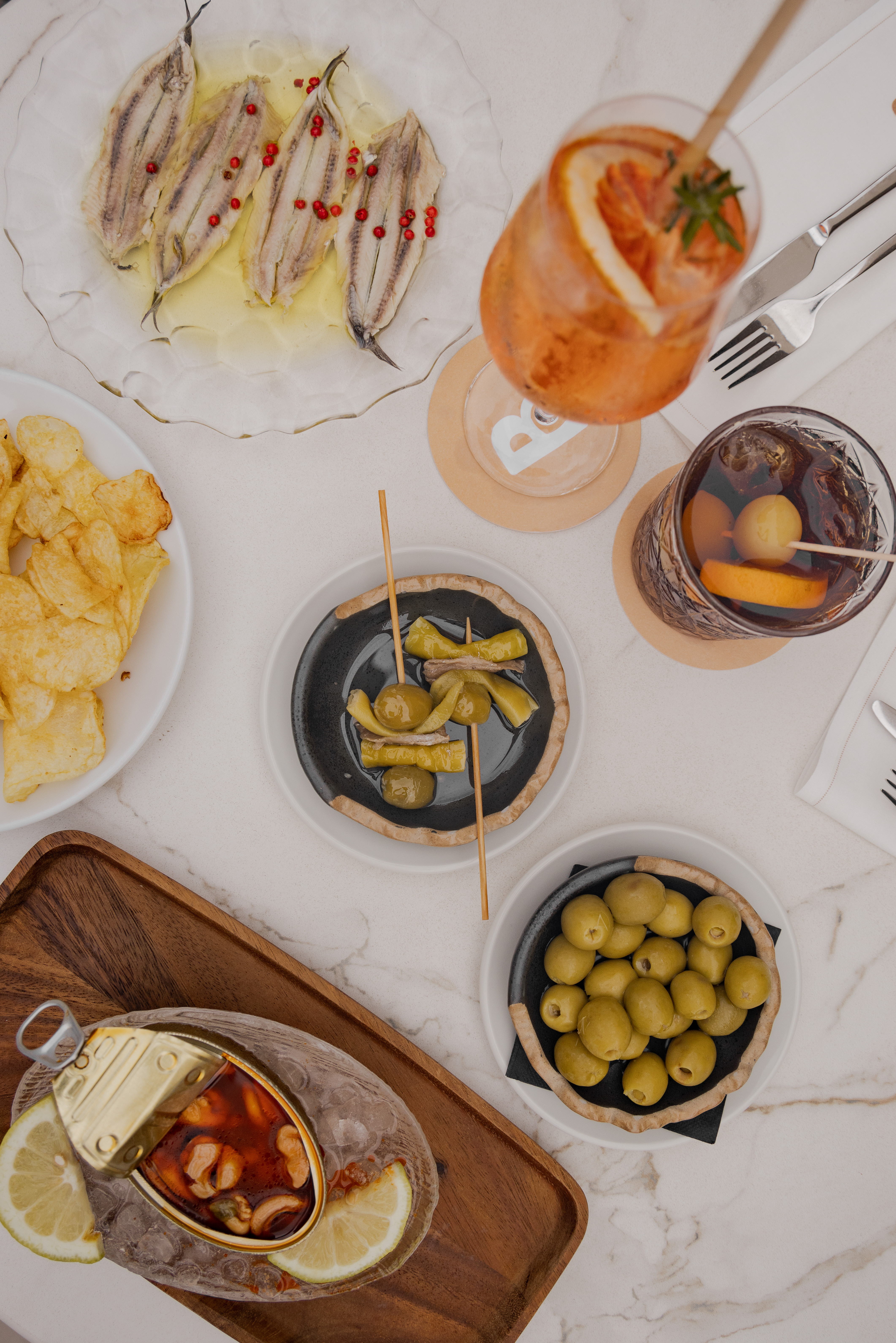 Spanish tapas feast: boquerones, olives, conservas, Gilda, chips, and cocktails.