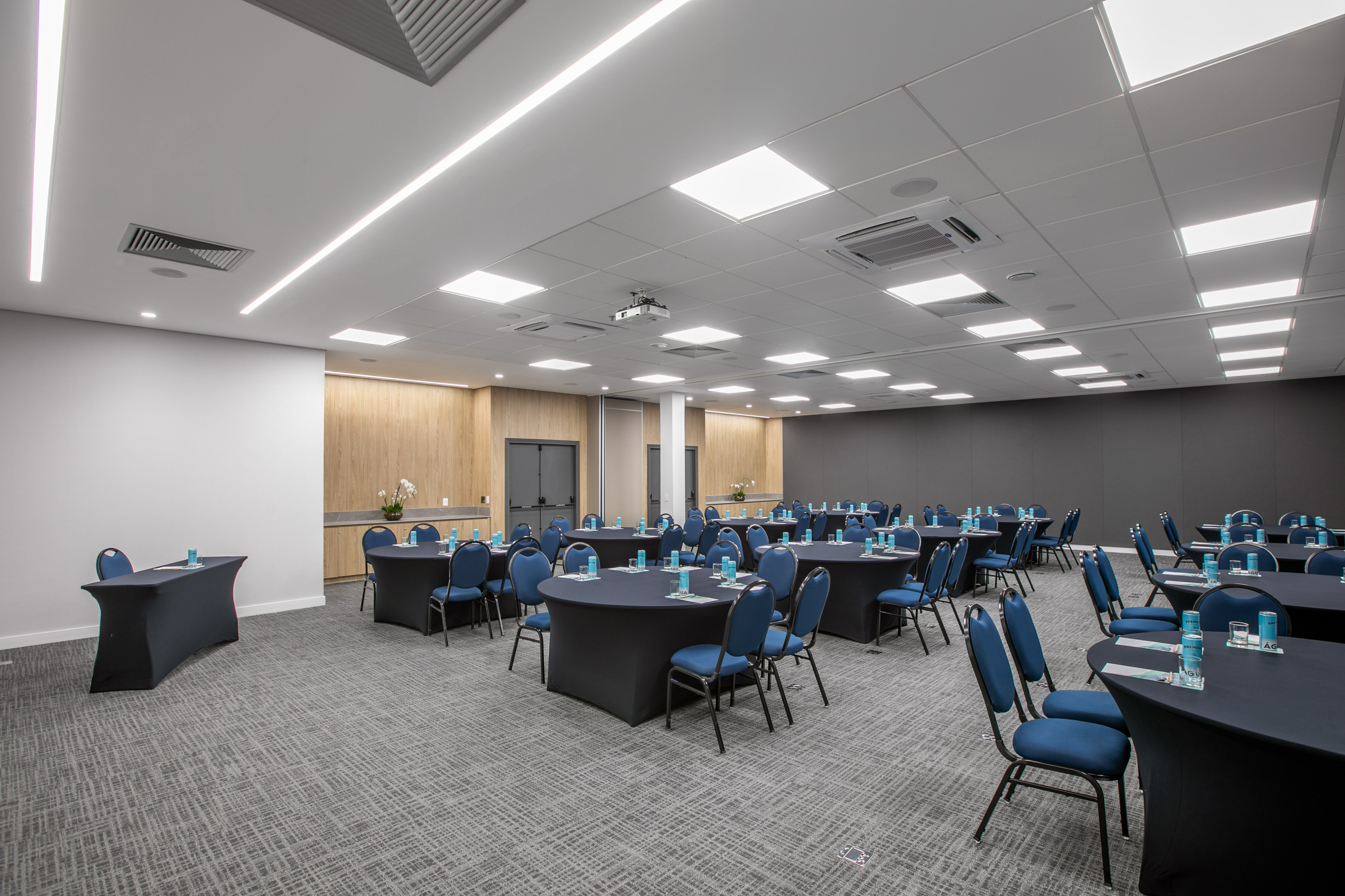 Modern corporate event space with round tables and blue chairs.
