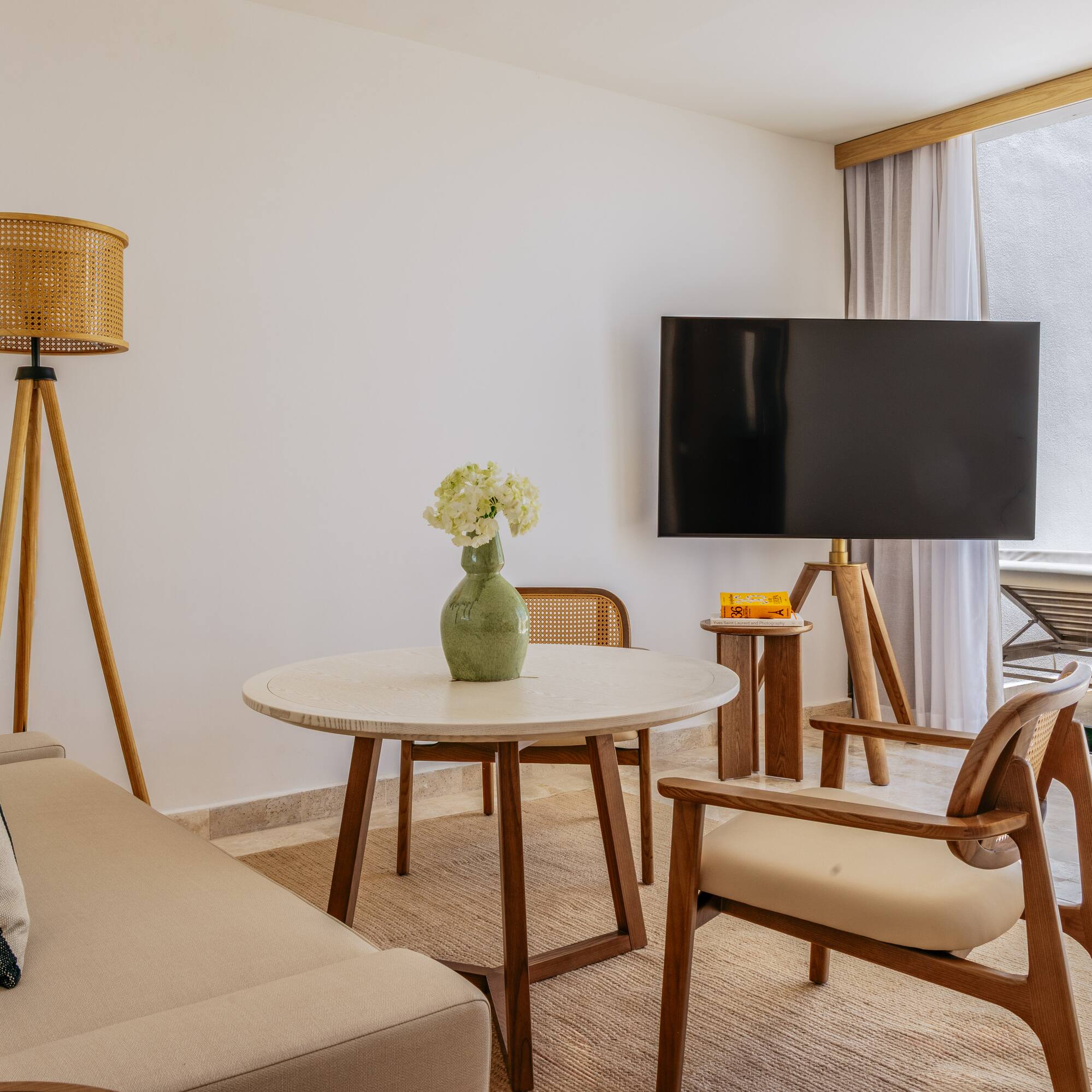 Modern living room with neutral sofa, wood furniture, TV, and balcony view.