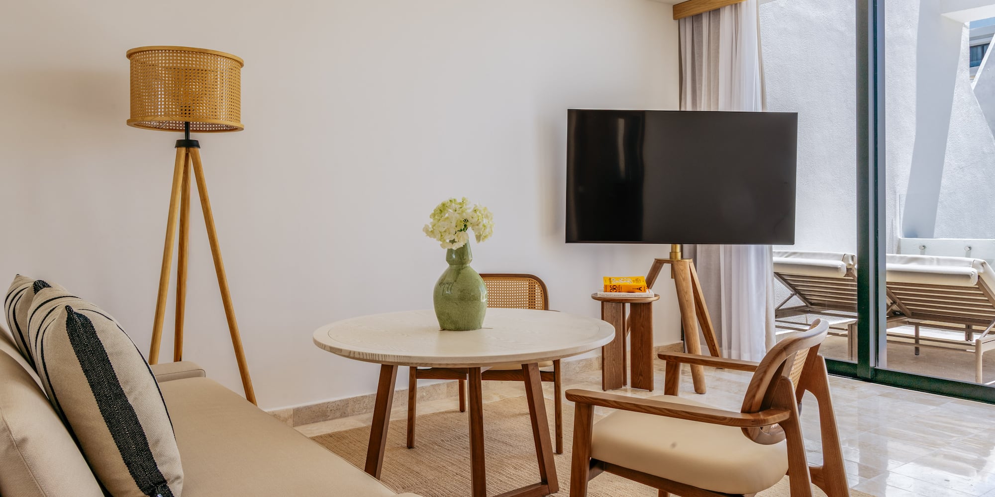 Modern living room with neutral sofa, wood furniture, TV, and balcony view.