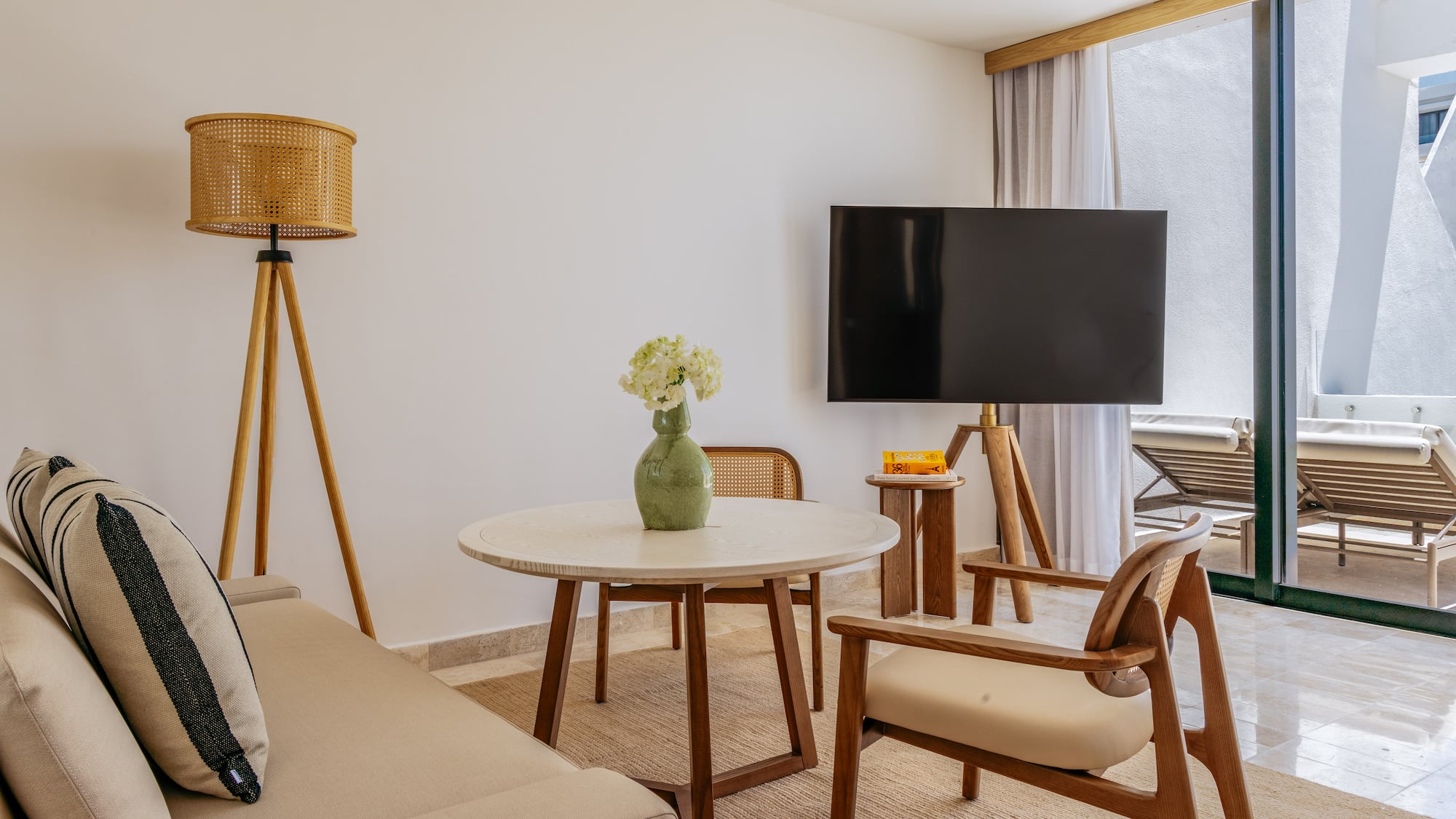 Modern living room with neutral sofa, wood furniture, TV, and balcony view.