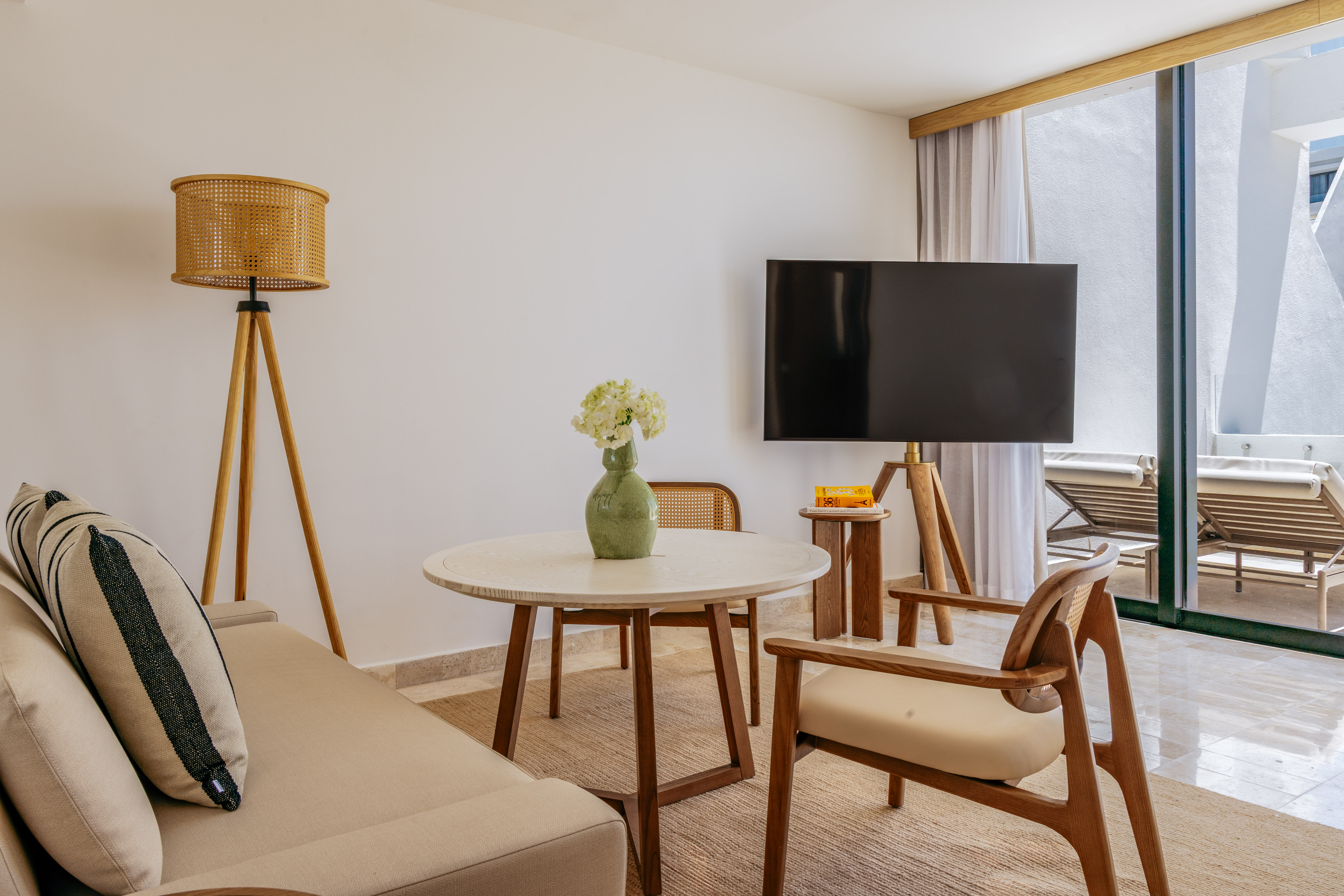 Modern living room with neutral sofa, wood furniture, TV, and balcony view.