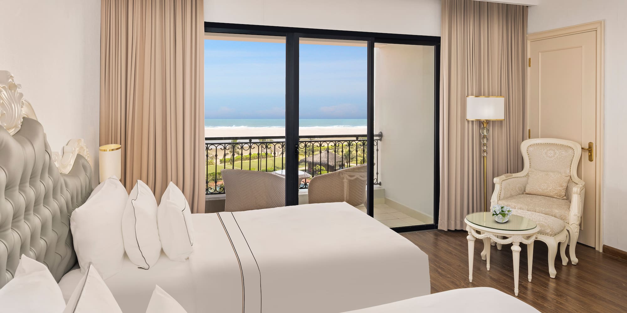 a room with two beds and a balcony overlooking the ocean