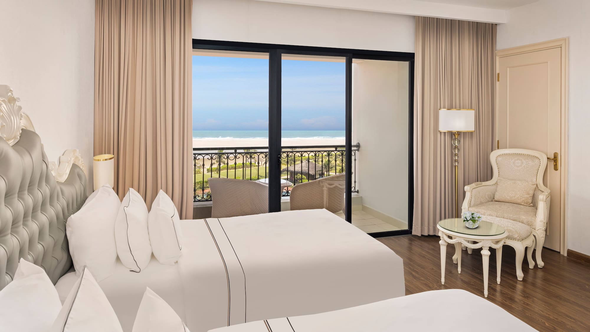 a room with two beds and a balcony overlooking the ocean