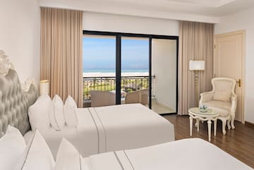 a room with two beds and a balcony overlooking the ocean