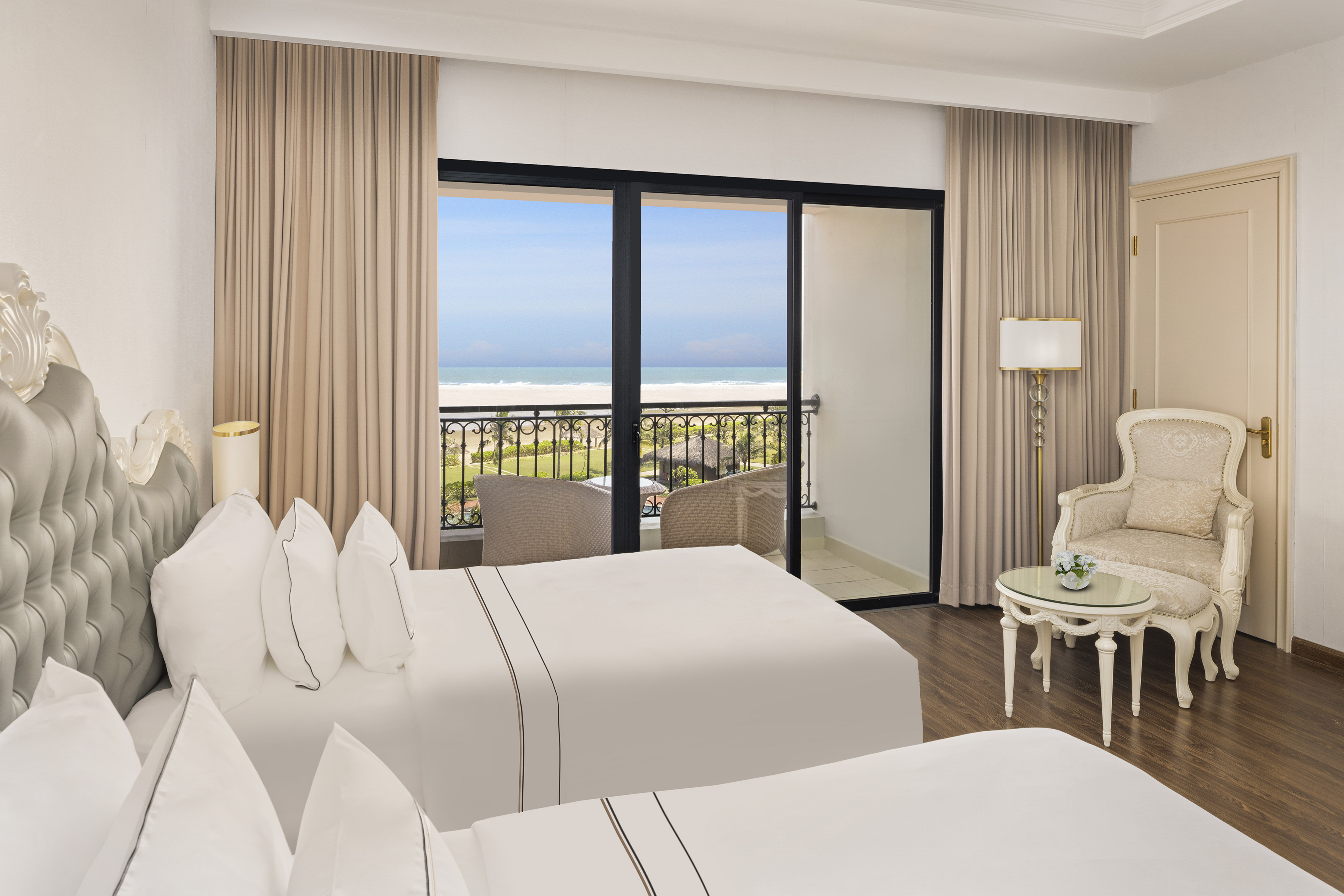a room with two beds and a balcony overlooking the ocean