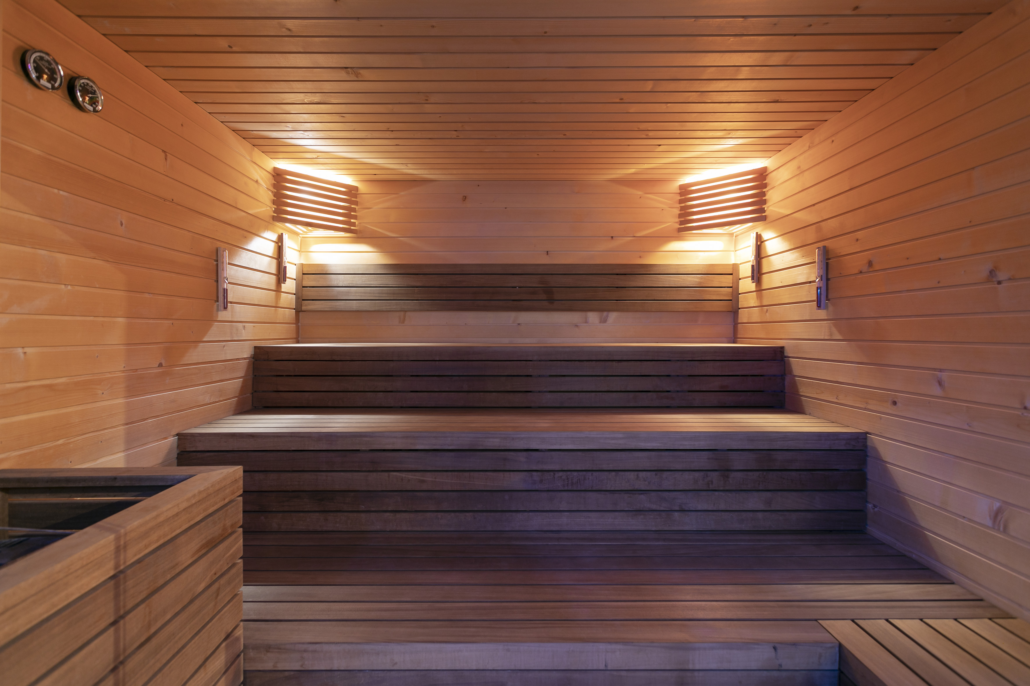Warm wooden sauna interior with tiered benches and soft lighting.